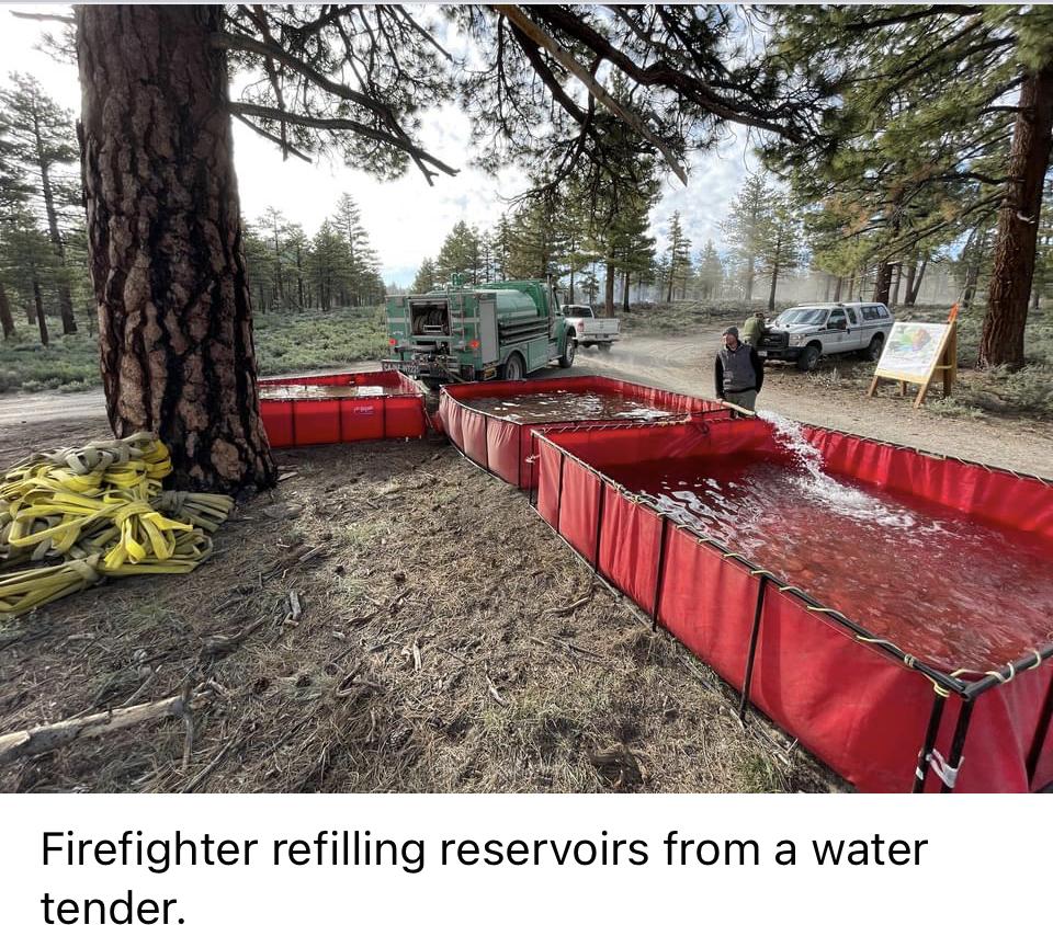 Image showing a Firefighter refilling red temporary plastic walled reservoirs from a water tender