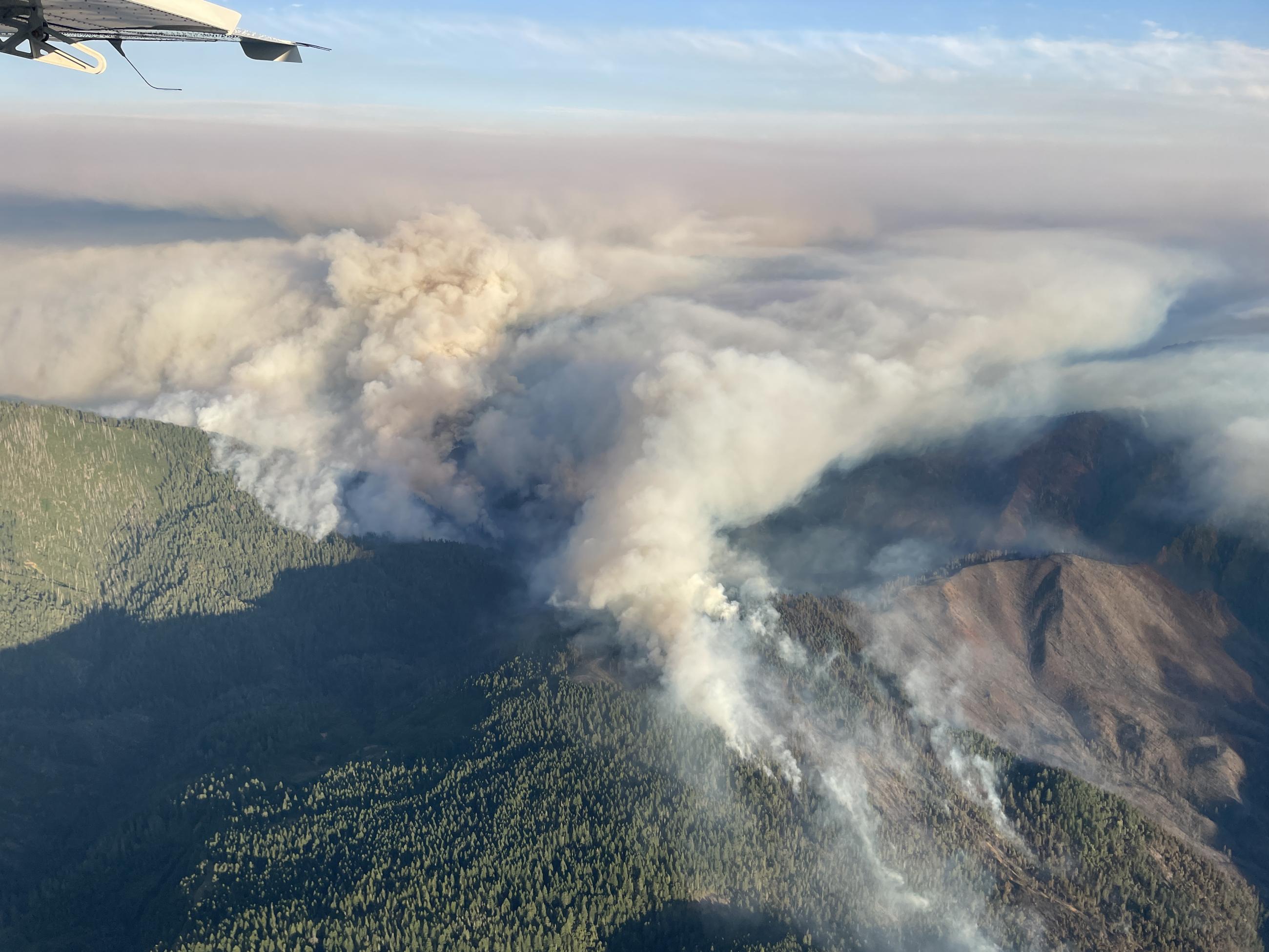 Ariel photo of fire burning over steep terrain.