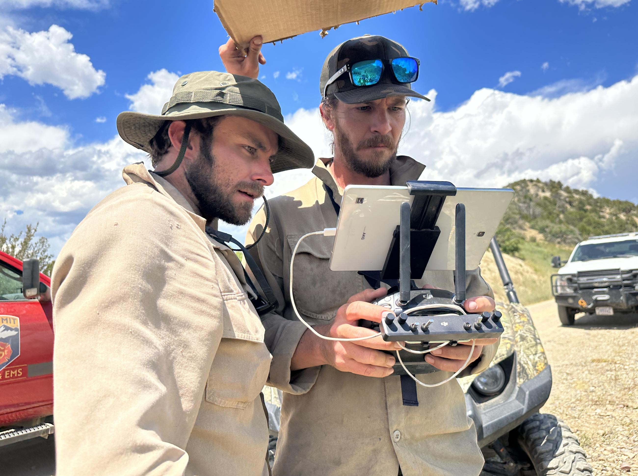 2 men look at a small monitor and controls for drone during firing operation