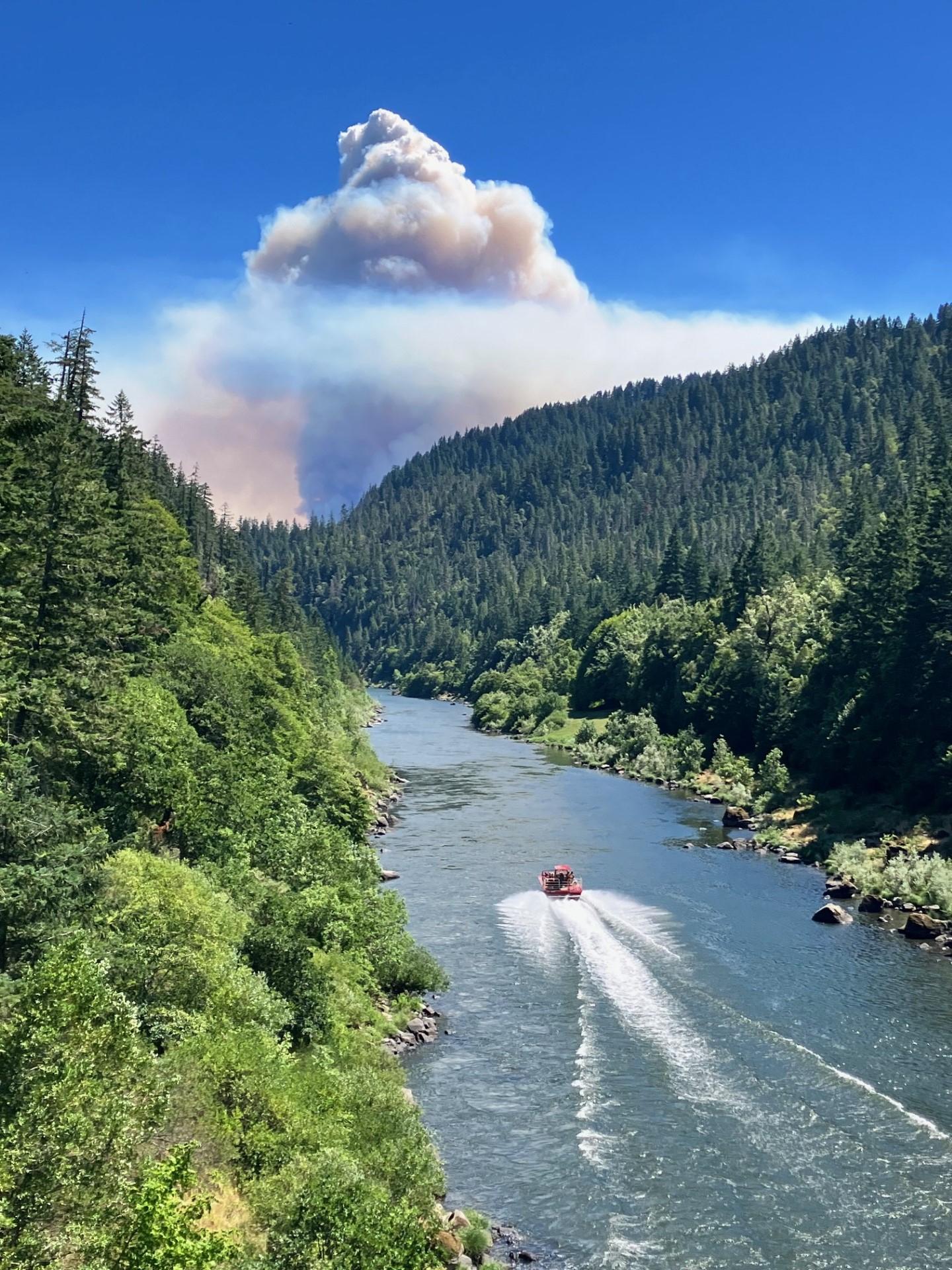A jet boat transports firefighters up the Rogue River on July 17, 2023. The Flat Fire smoke column can be seen in the background.