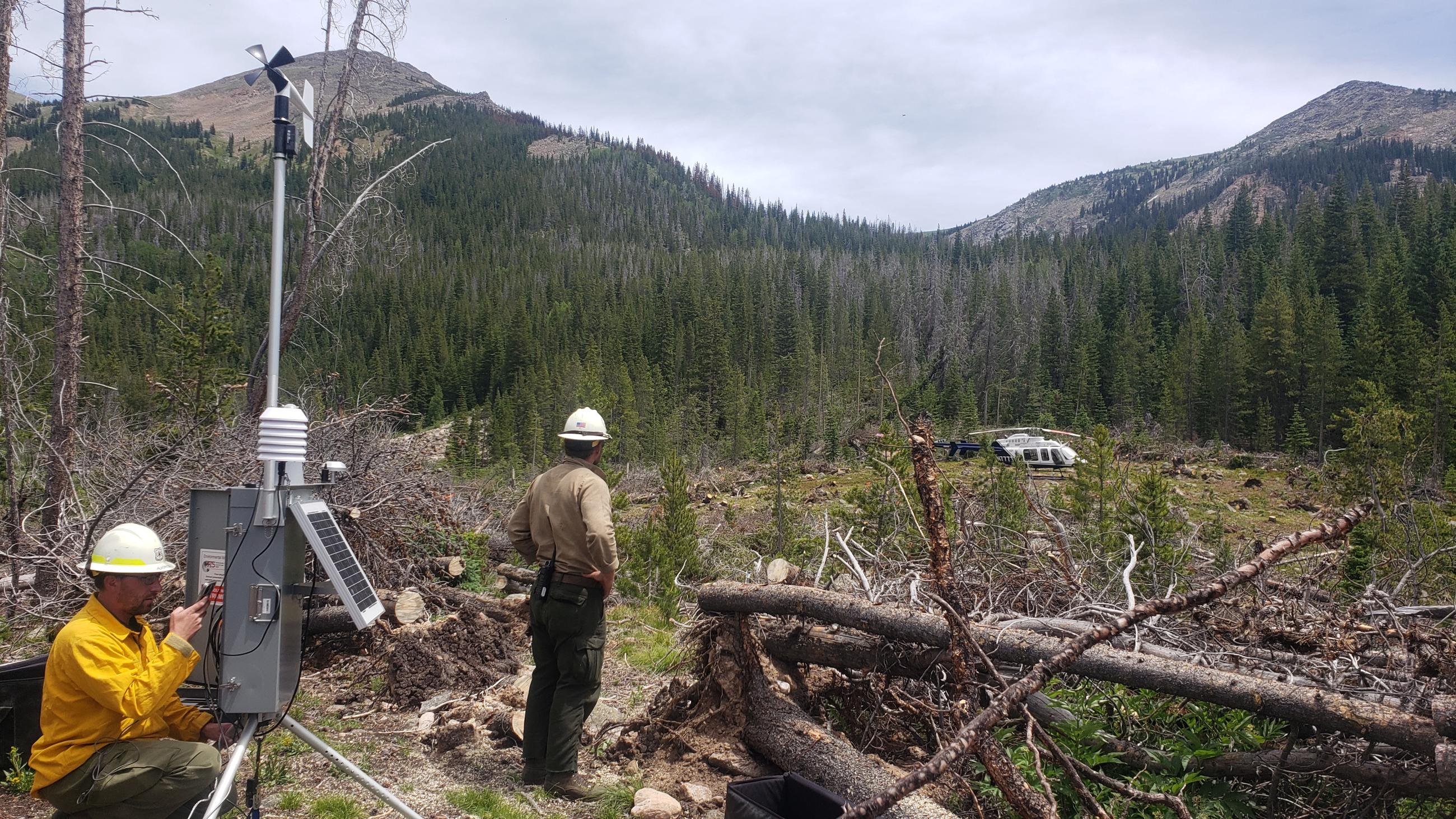 Picture shows fire personnel in a hillside with a remote automated weather station. 