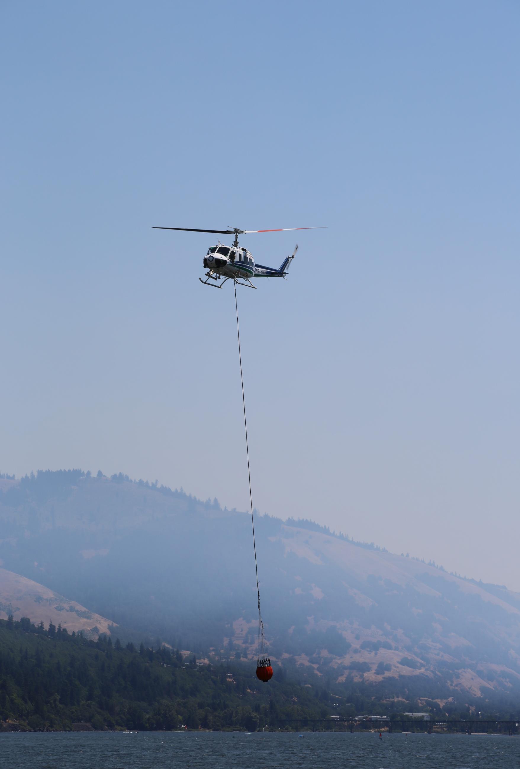 Helicopter dipping for water in the Columbia River from long-line bucket configuration.
