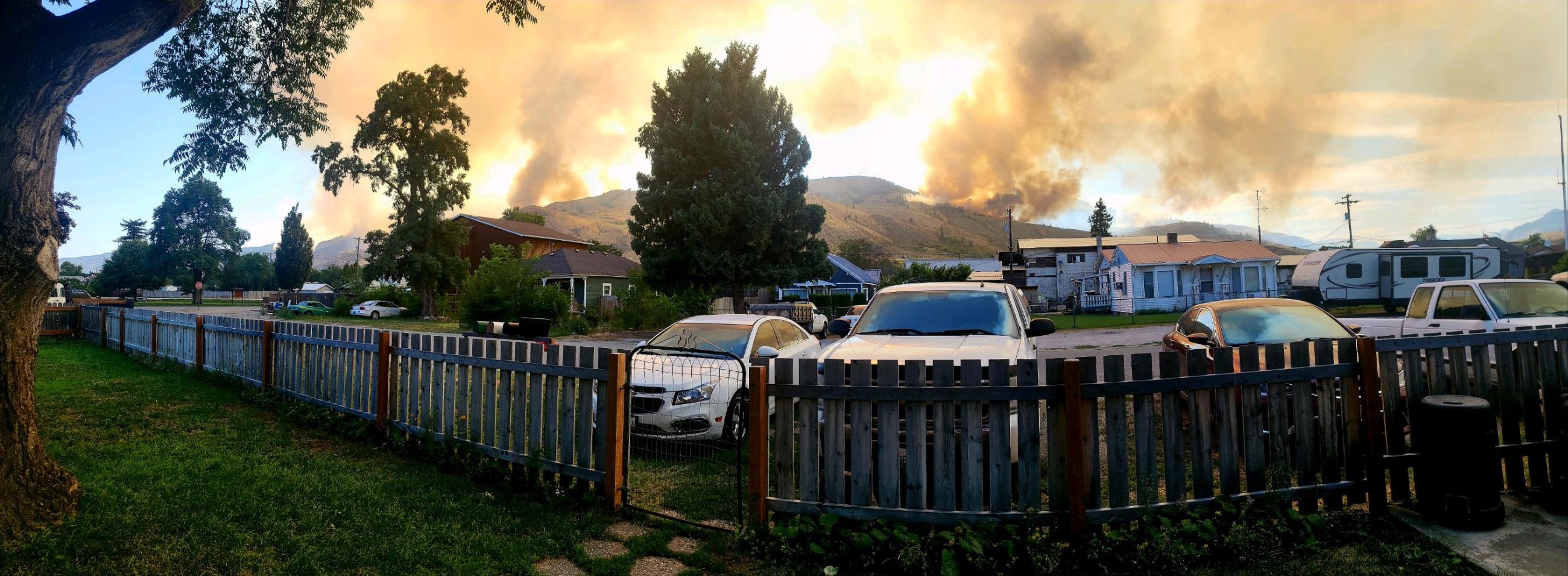 View from someone's yard of neighborhood in foreground with burning hills in background