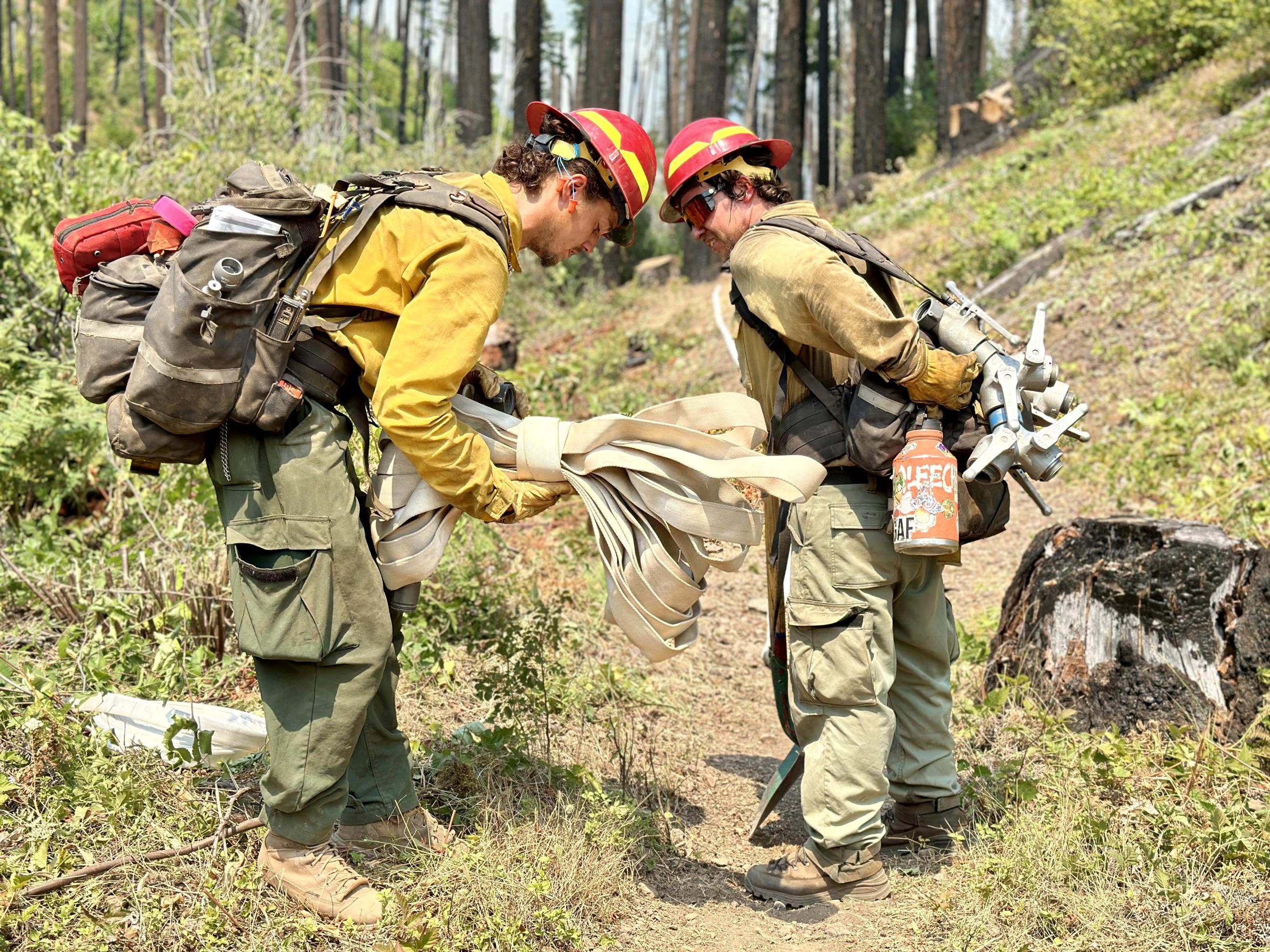 Two firefighters prepare a hoselay at Bedrock Campground.