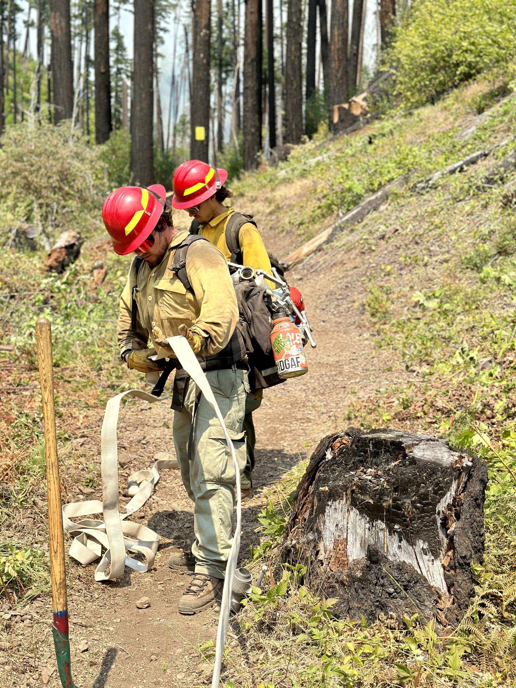 Two firefighters prepare a hoselay at Bedrock Campground.
