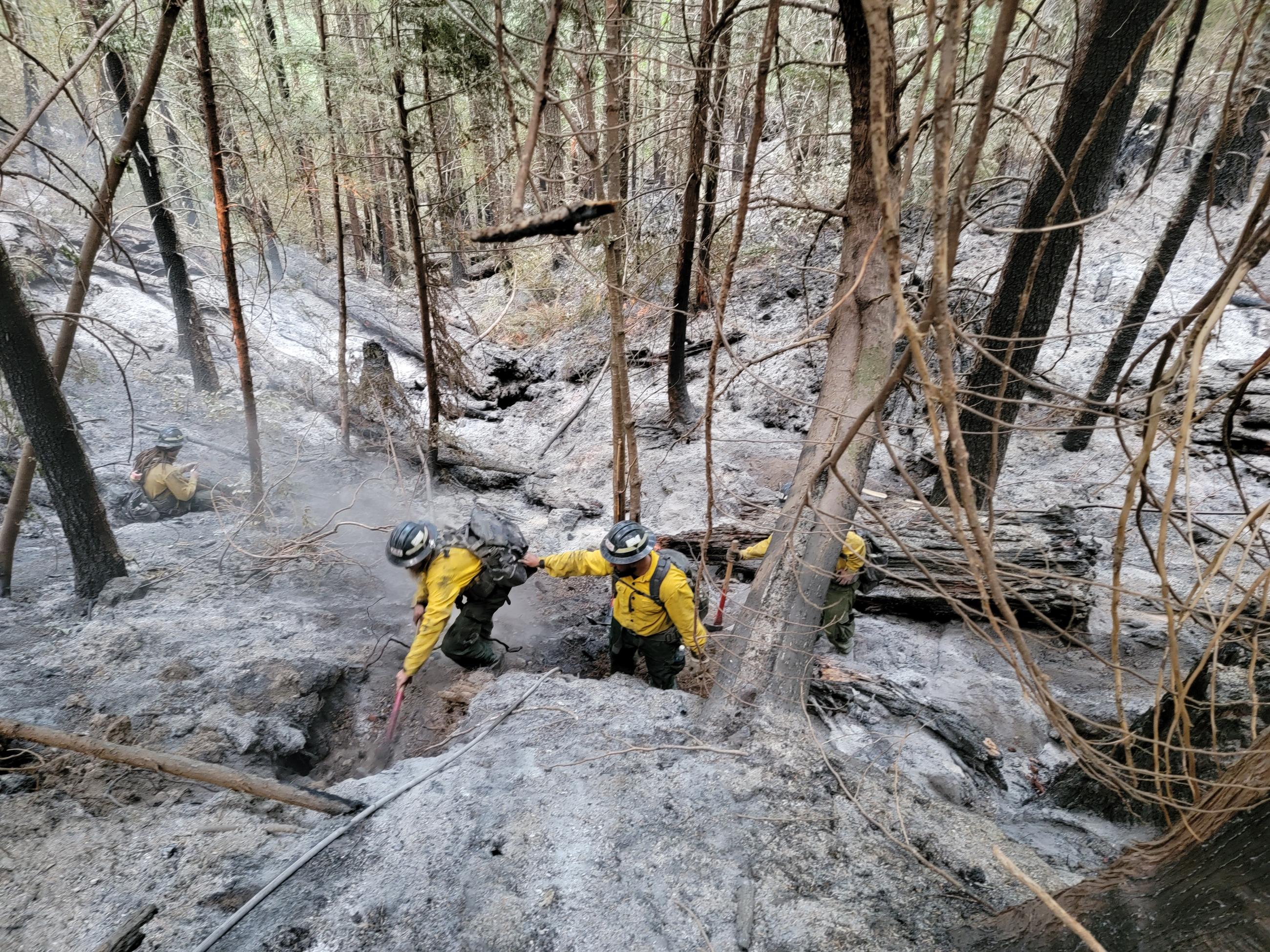 Firefighters mopping up on very steep ground with deep ash