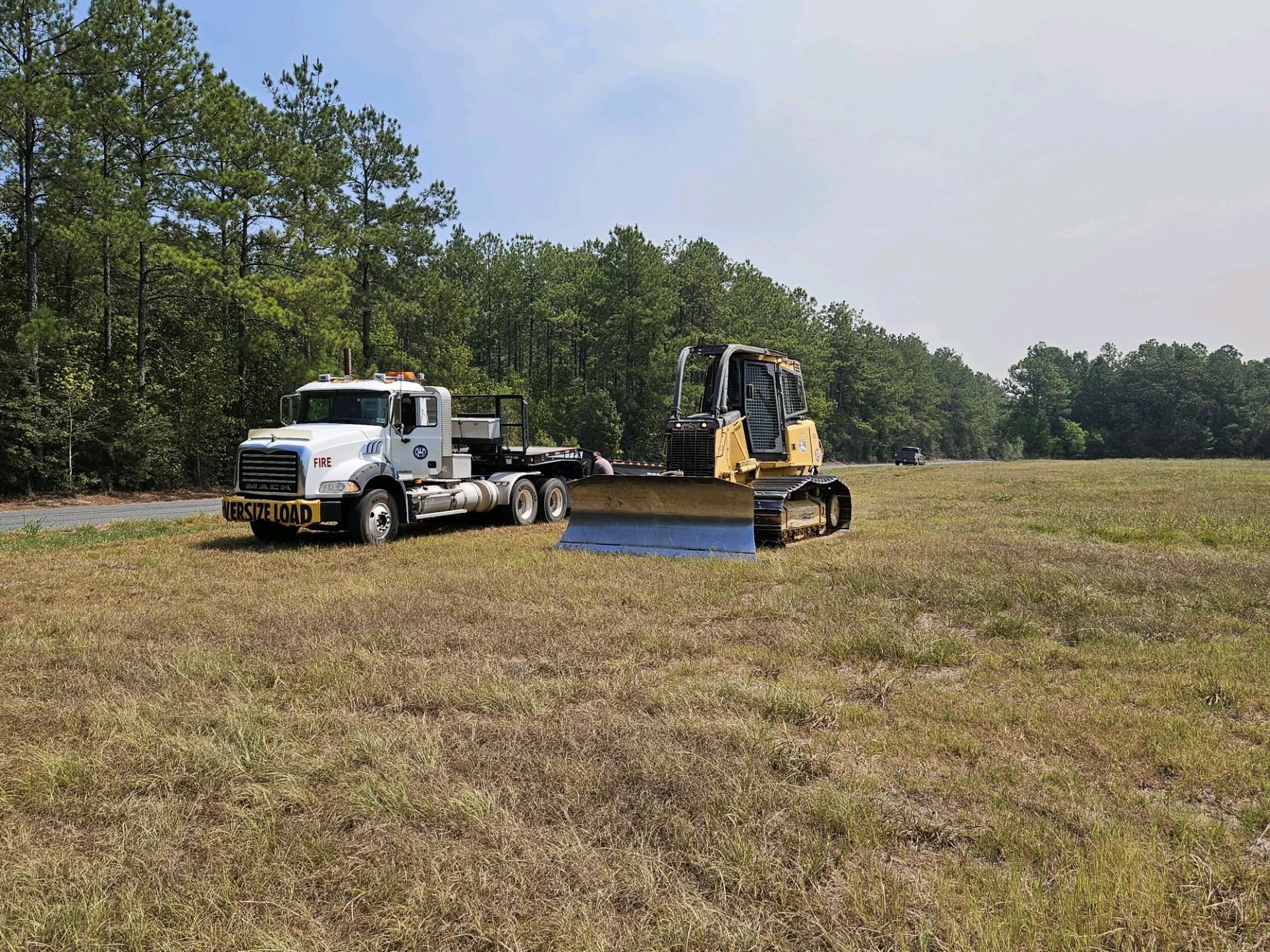 Semi truck and dozer parked in a grass field staged to begin work on the Tiger Island Fire.