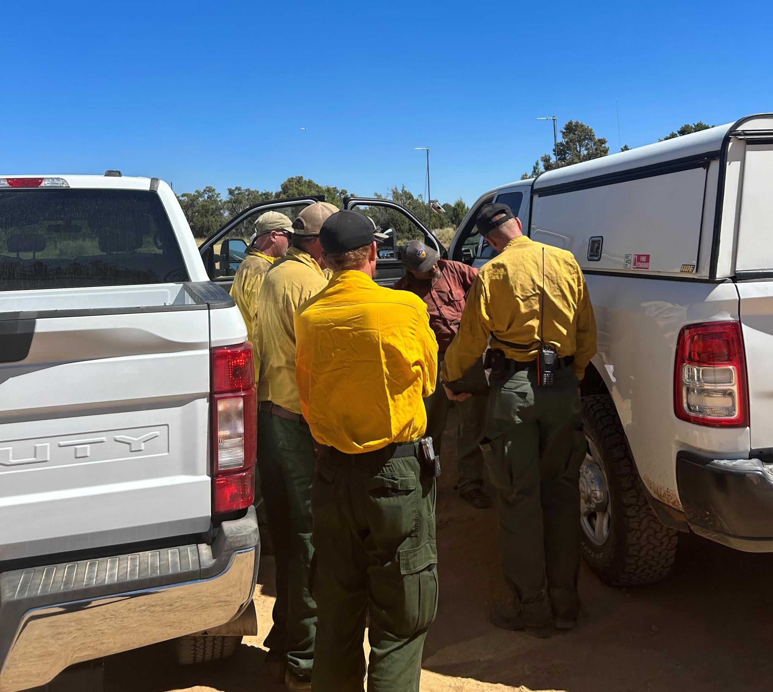 Fire managers discuss around a map hung on the side of a Forest Service truck.