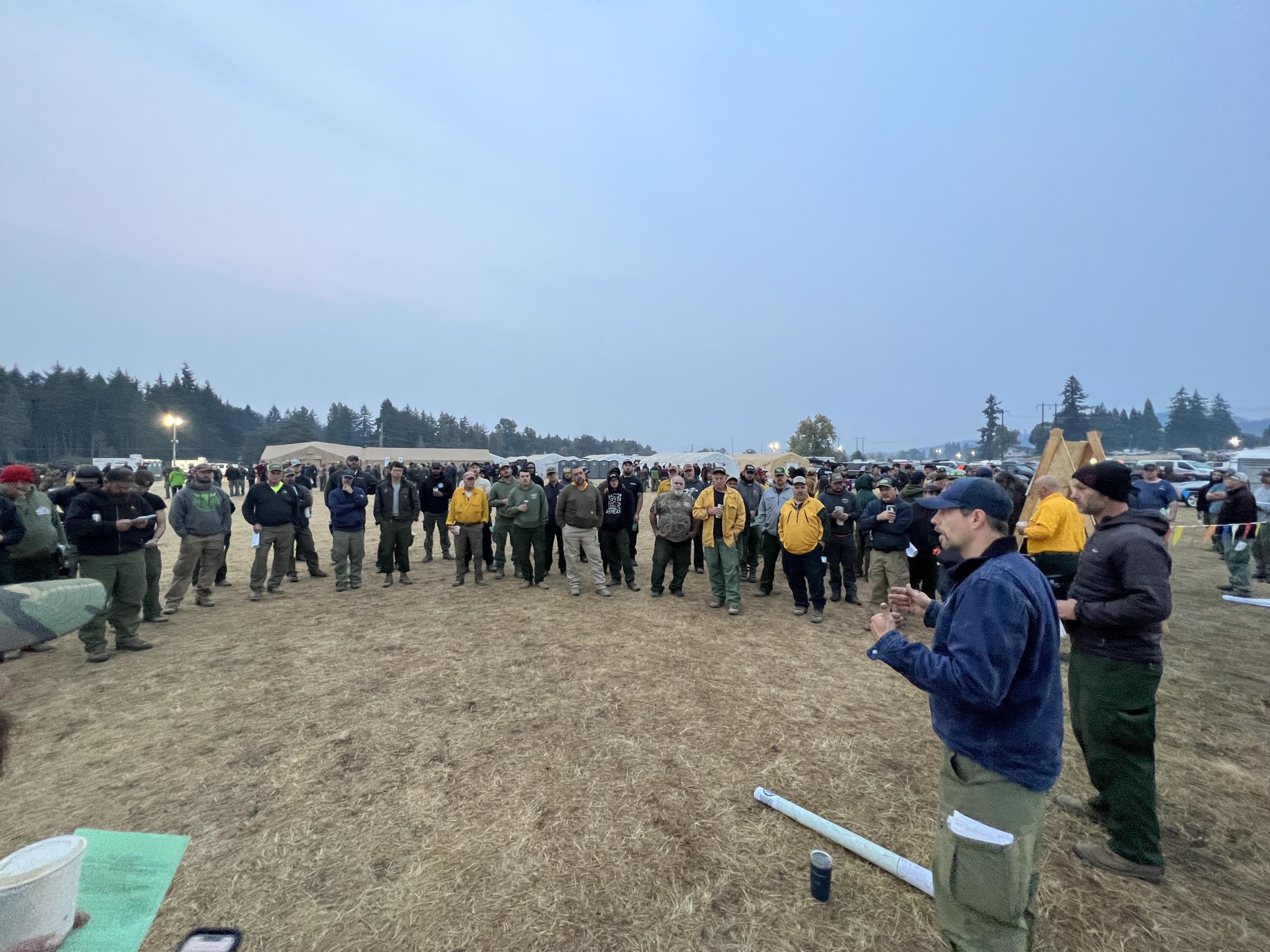 A group of firefighters in a semi-circle conduct a meeting.