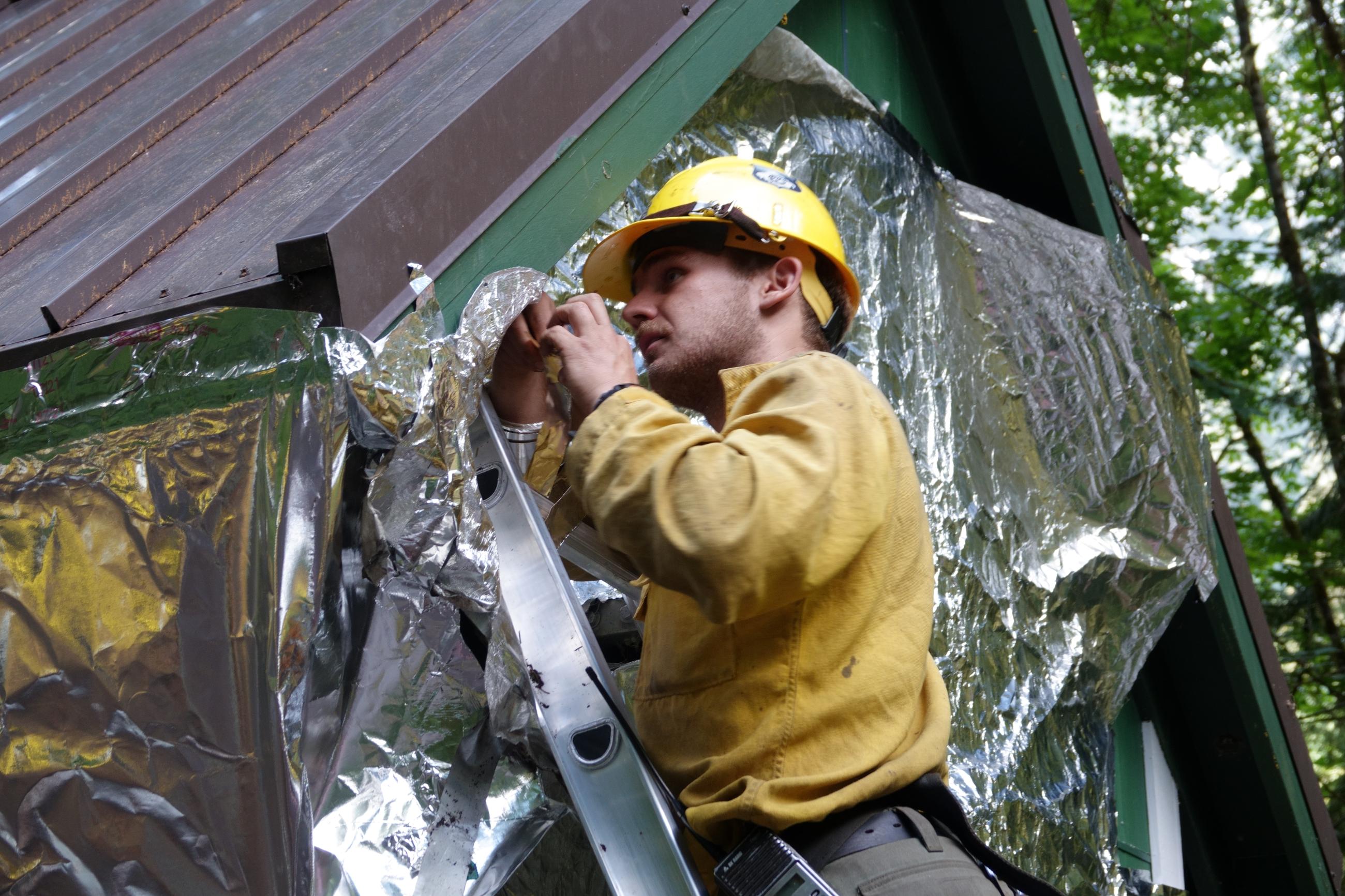 A firefighter wraps a building a silver colored protective covered