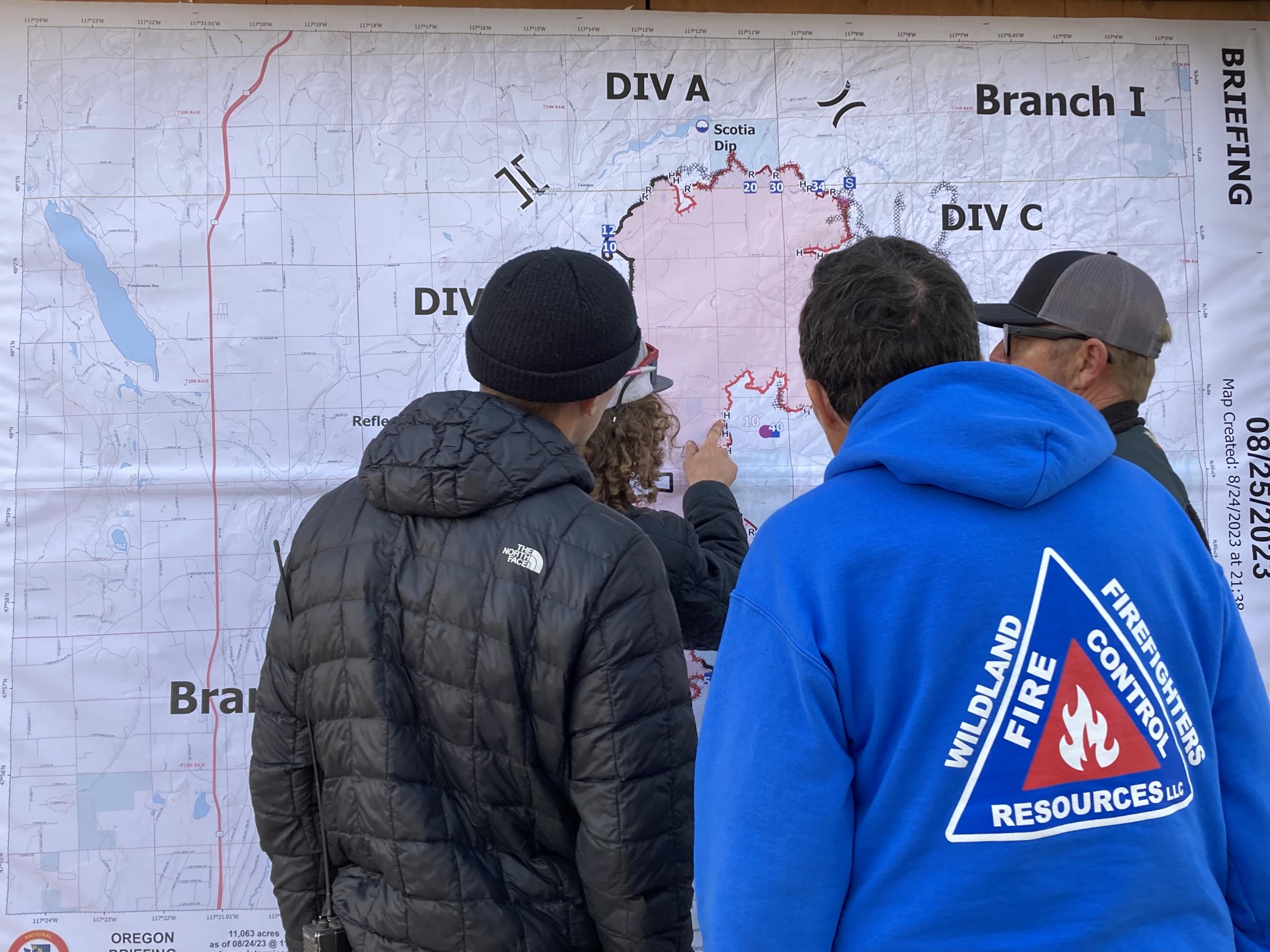 4 people in front of a large fire map discussing