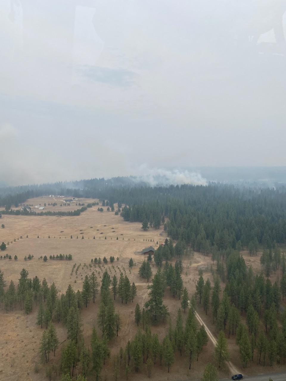 Mix of forest and agricultural land with smoke in distance