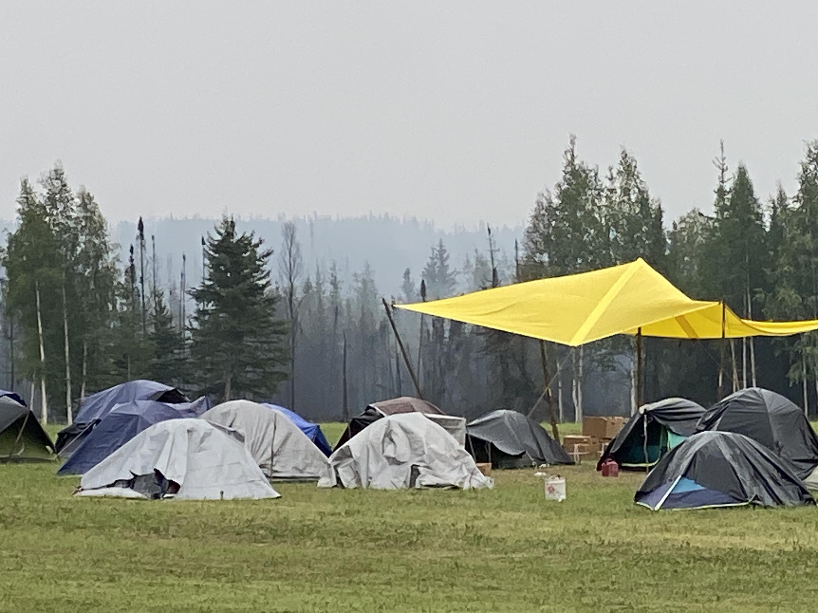 Firefighters camp in a green meadow at the Pogo Mine Road Fire #191.