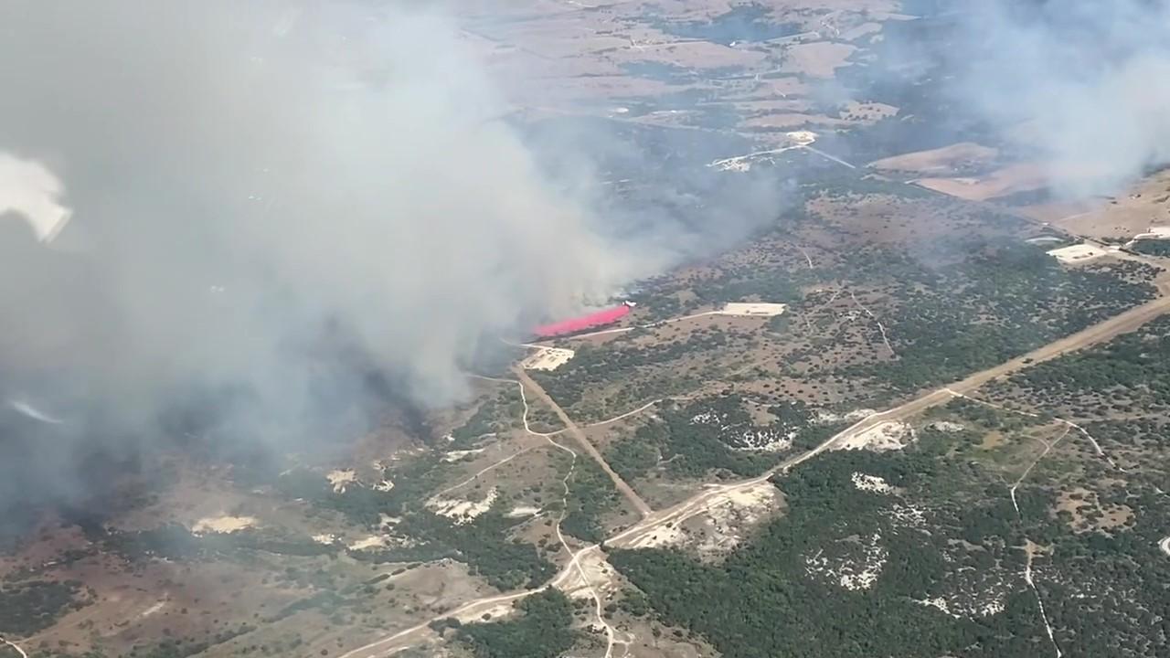 Aerial View of Large airtanker plane dropping red fire retardant over fire