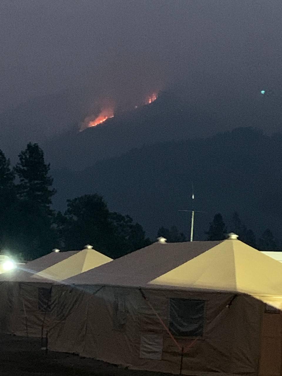 Large Yurts at night with a ring of fire burning in the hills above a fire camp located in Orleans