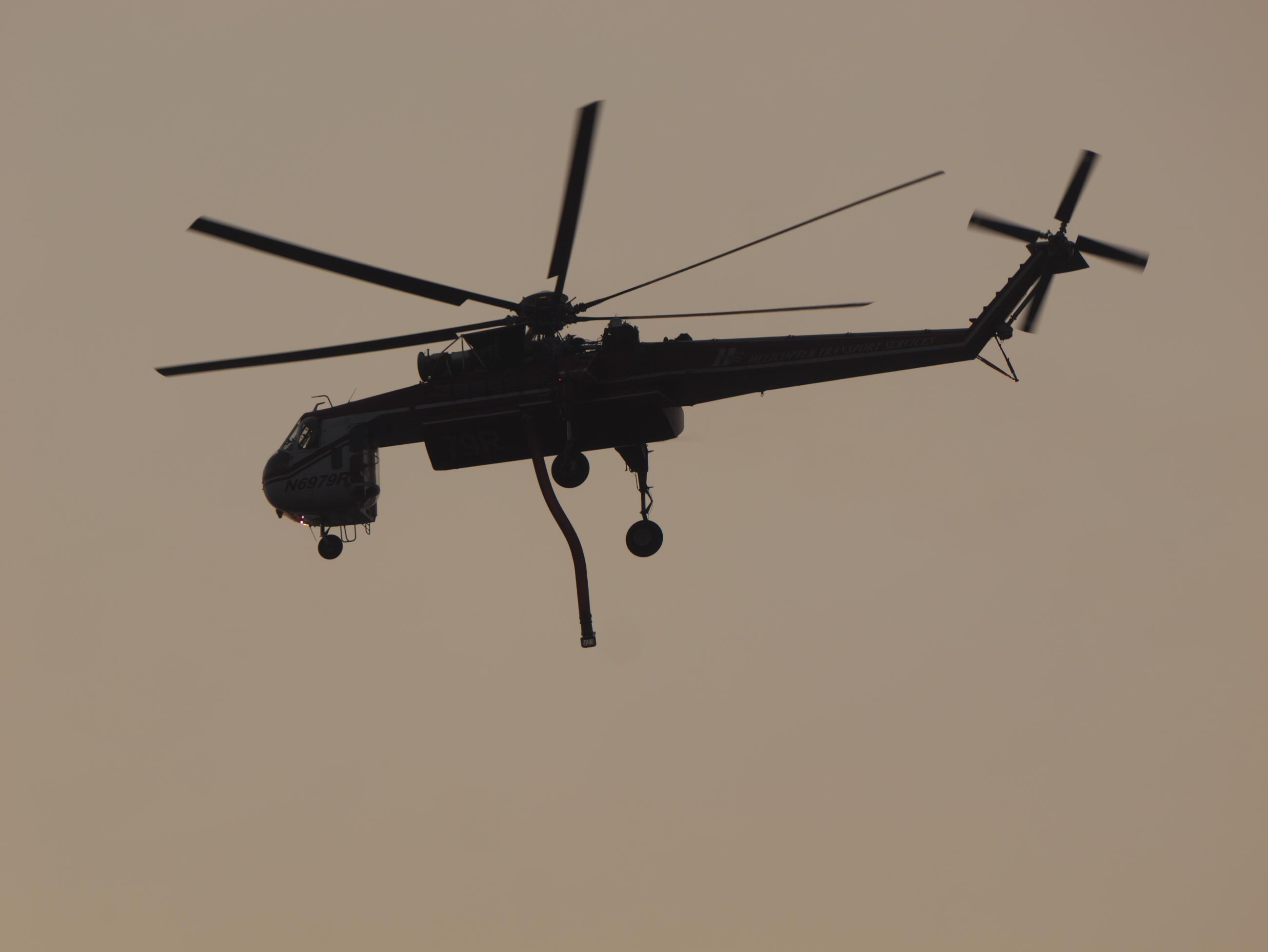 The silhouette of a helicopter with a dangling snorkle hose.