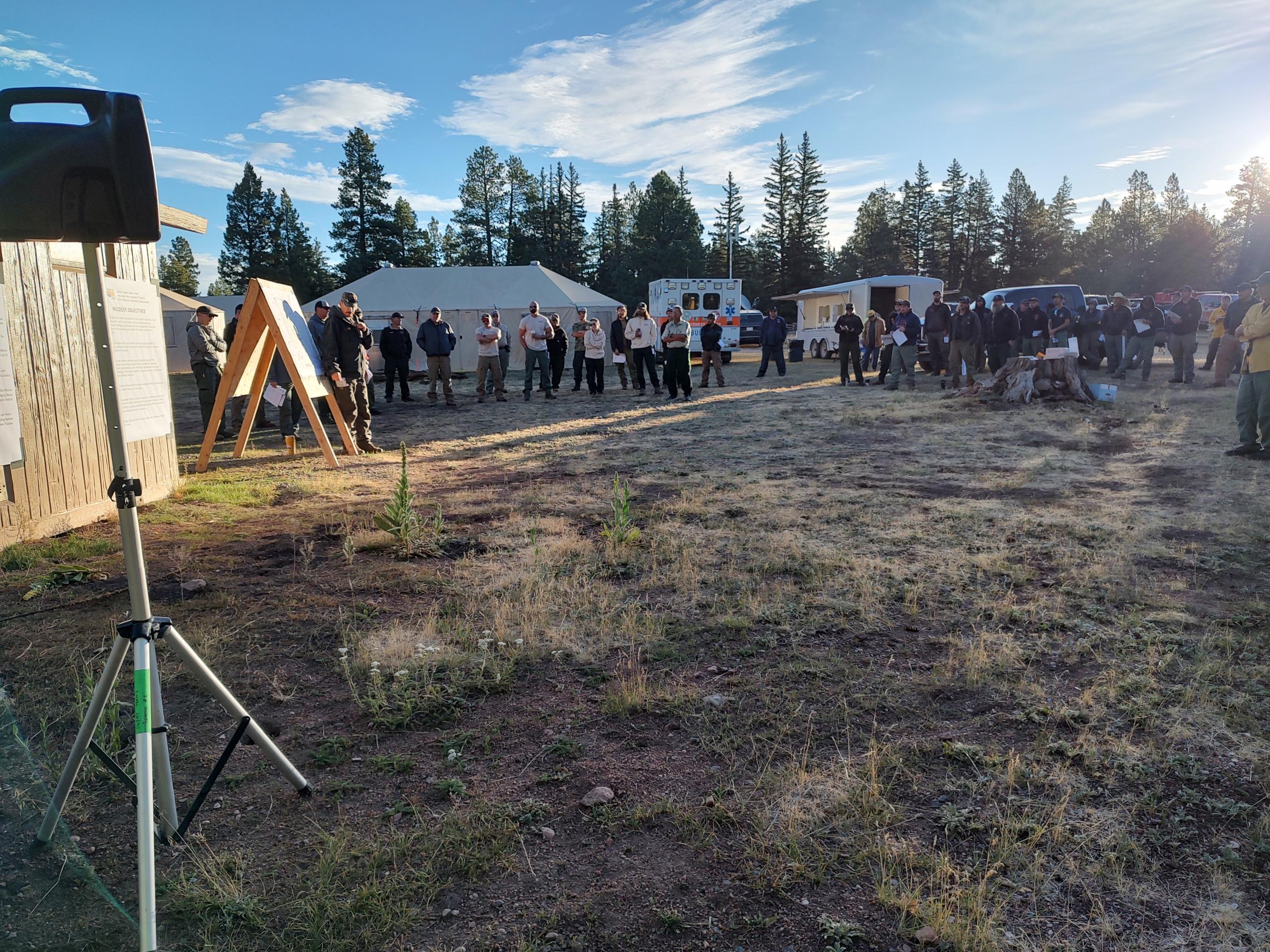 Image is of a photo of a group of people surrounding a board with a fire map. 