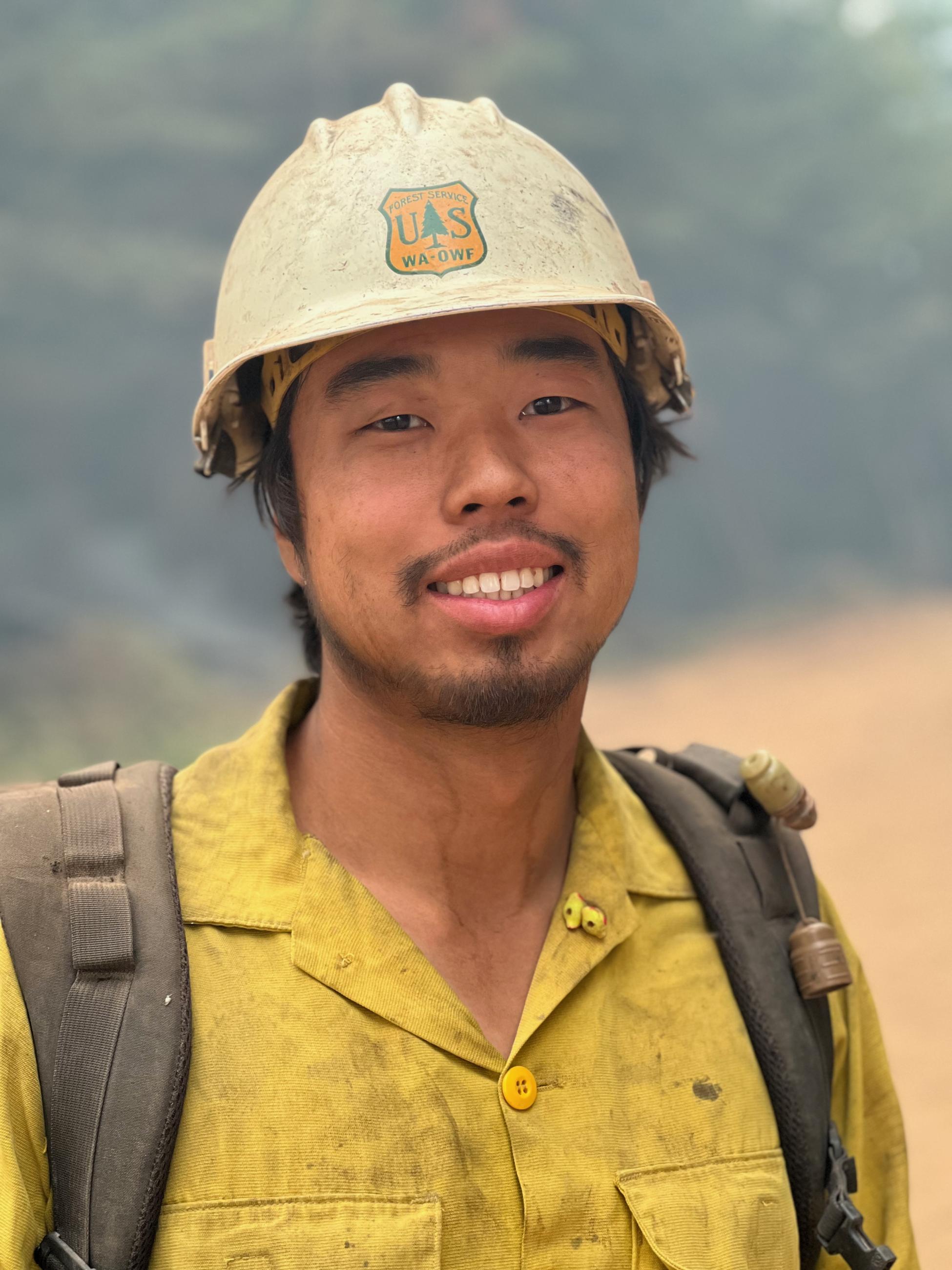 A portrait of a firefighter in yellow shirt and white helmet.