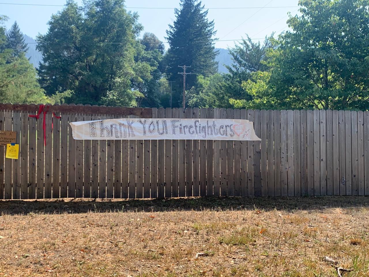 A handmade sign hung on a fence that reads "thank you firefighters"