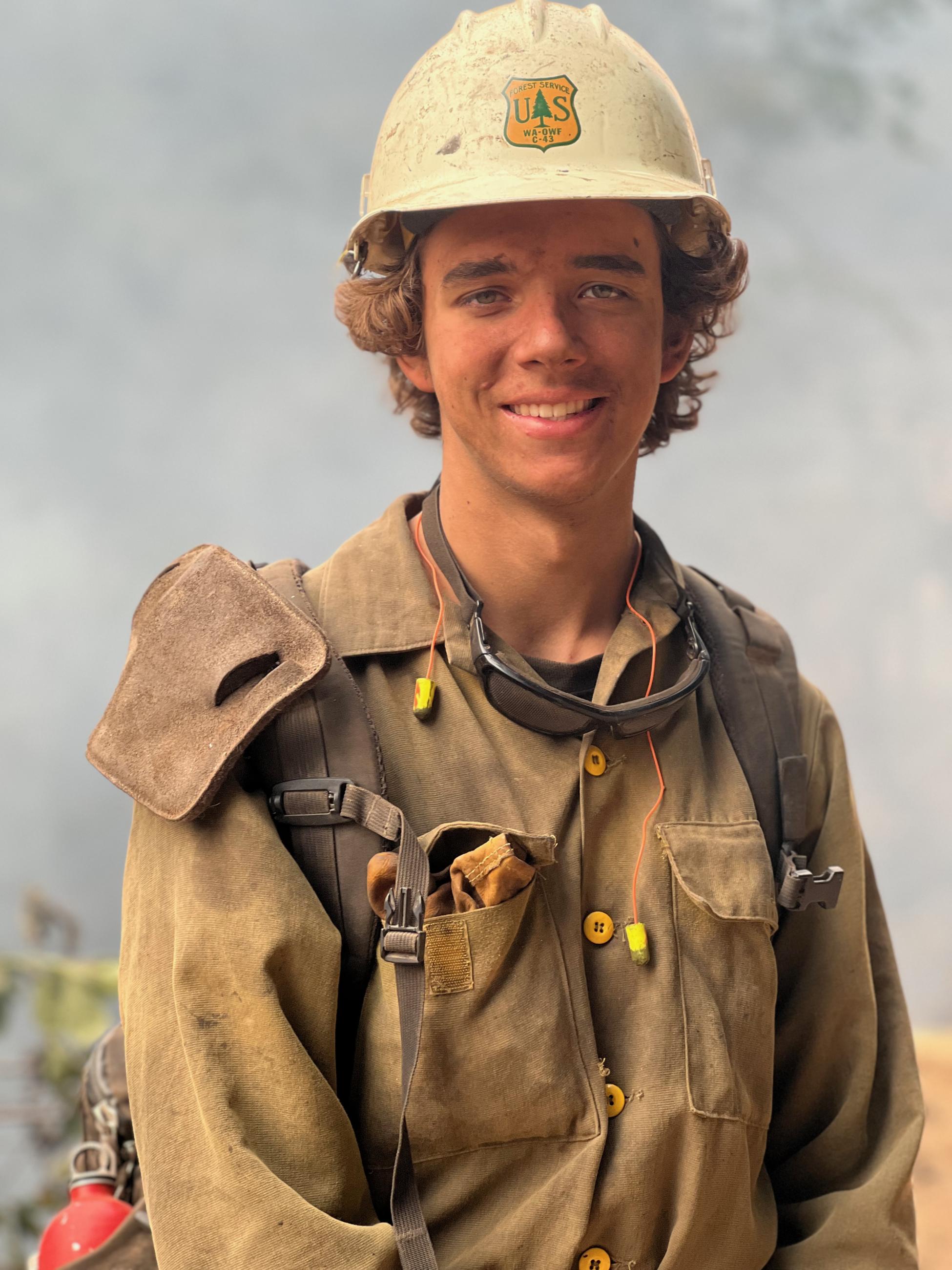 A portrait of a firefighter in protective gear, including a helmet and yellow fire shirt
