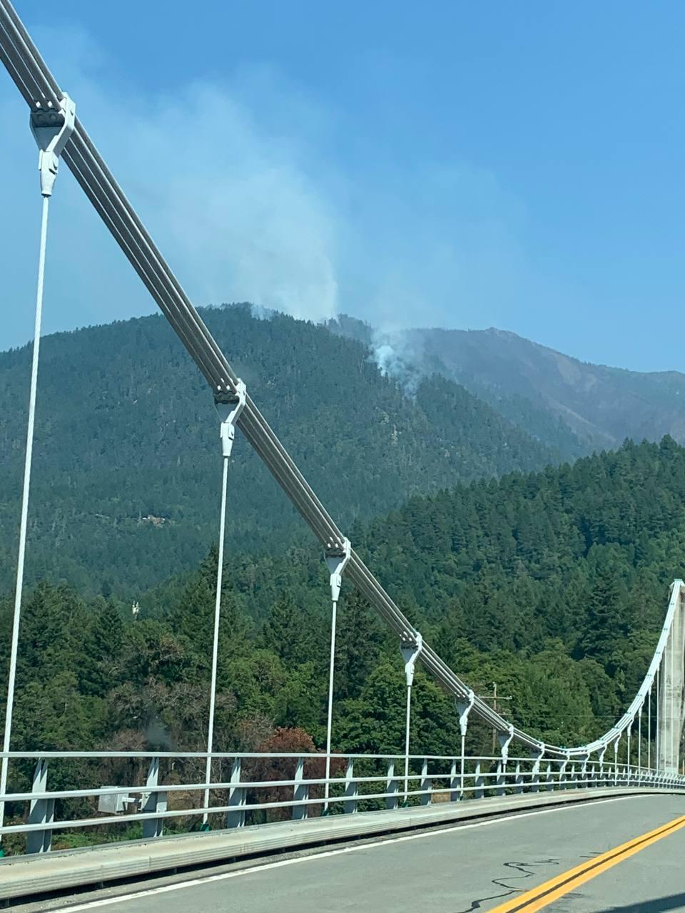 A plume of smoke rising in the mountains as seen from Orleans Bridge