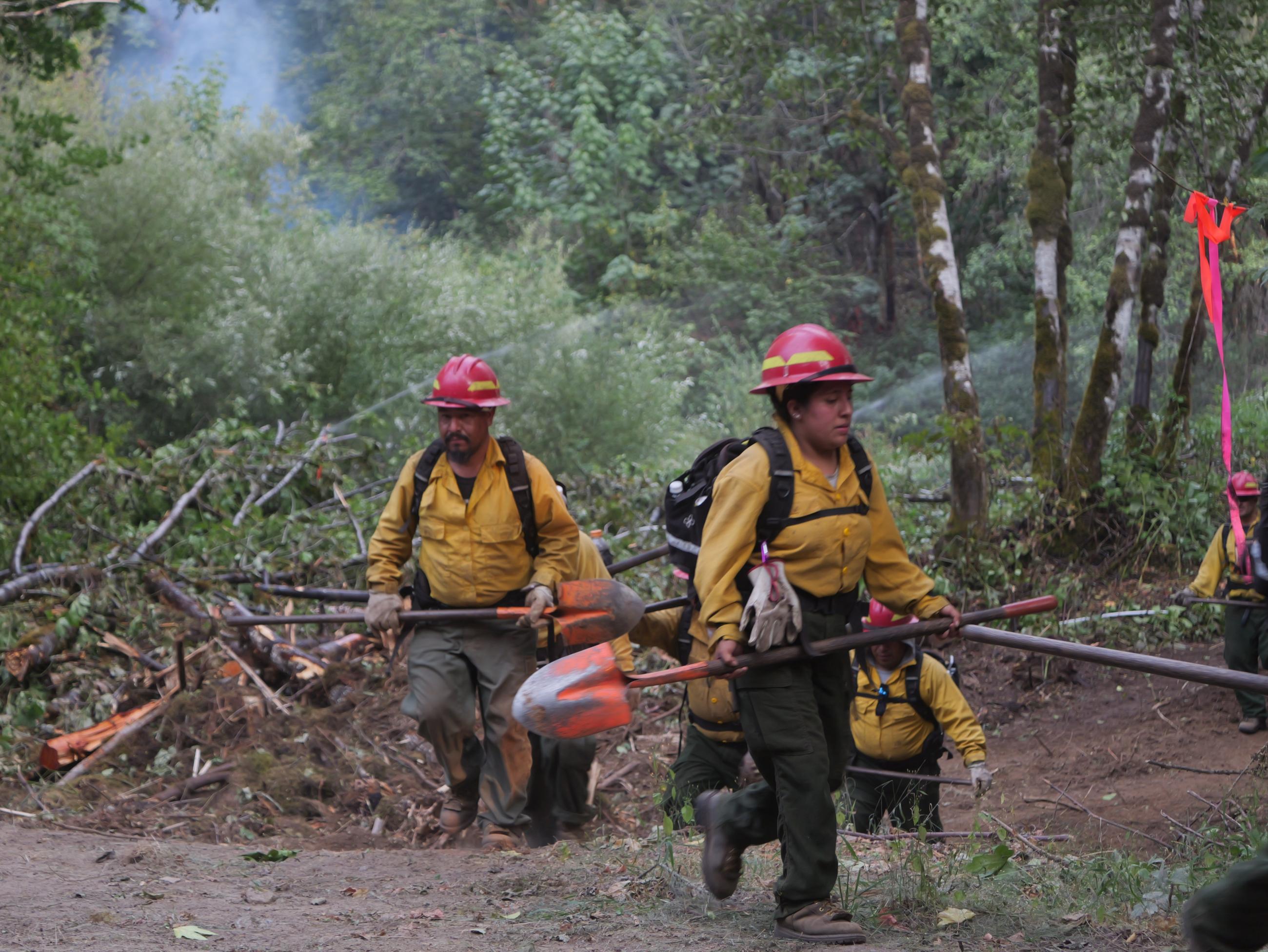 Members of a hand crew are seen coming off the fire line on August 24, 2023