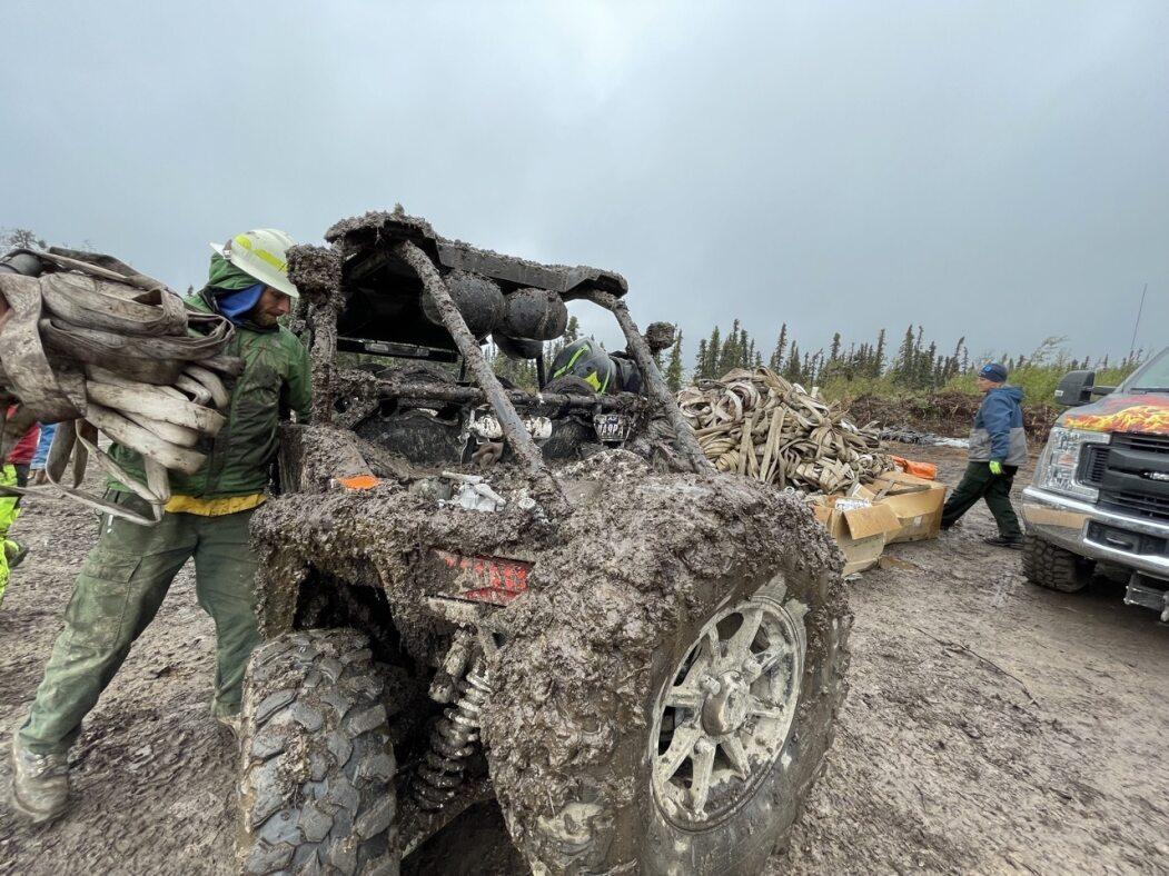 Photo of a very muddy all terrain vehicle that has been used for hauling water hose. 