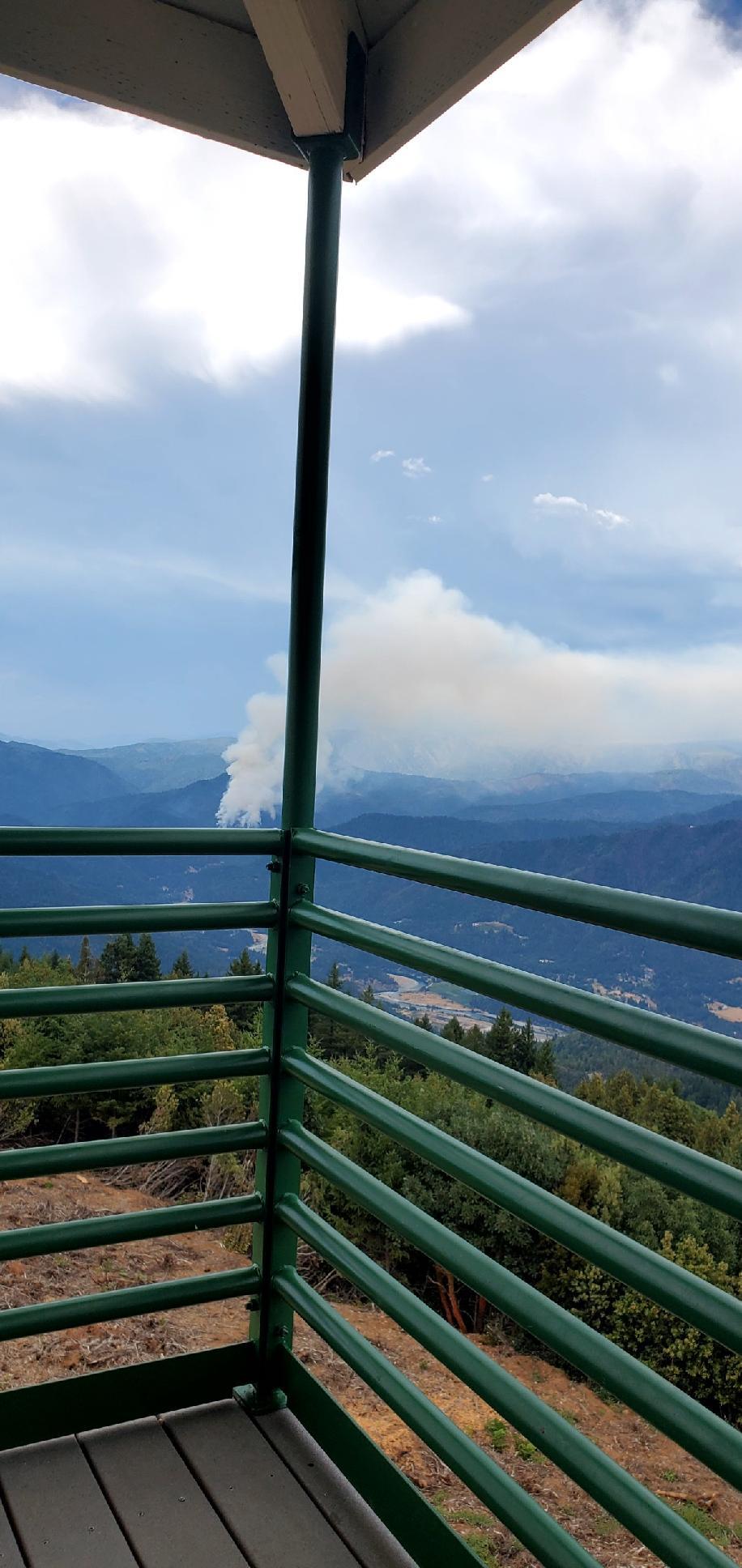 Smoke rising from the mountains, as seen from the balcony of a fire lookout