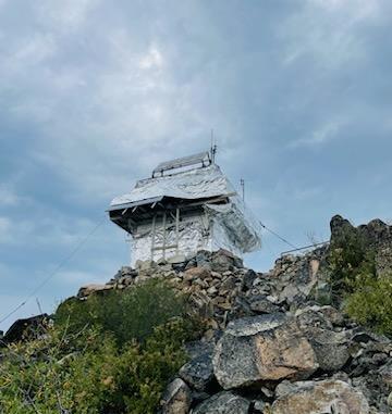 A small building sitting on a rock covered with silver fire-resistant wrapping