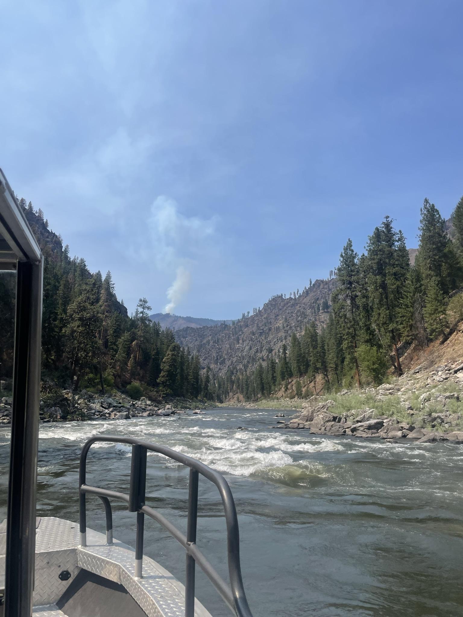 View of a smoke column in the distance from a boat traveling the Salmon River