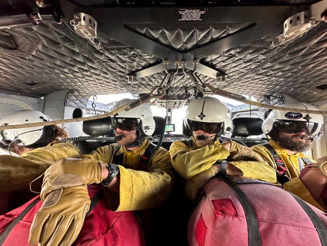 Fire rappelers wait ready in a helicopter to respond to fire
