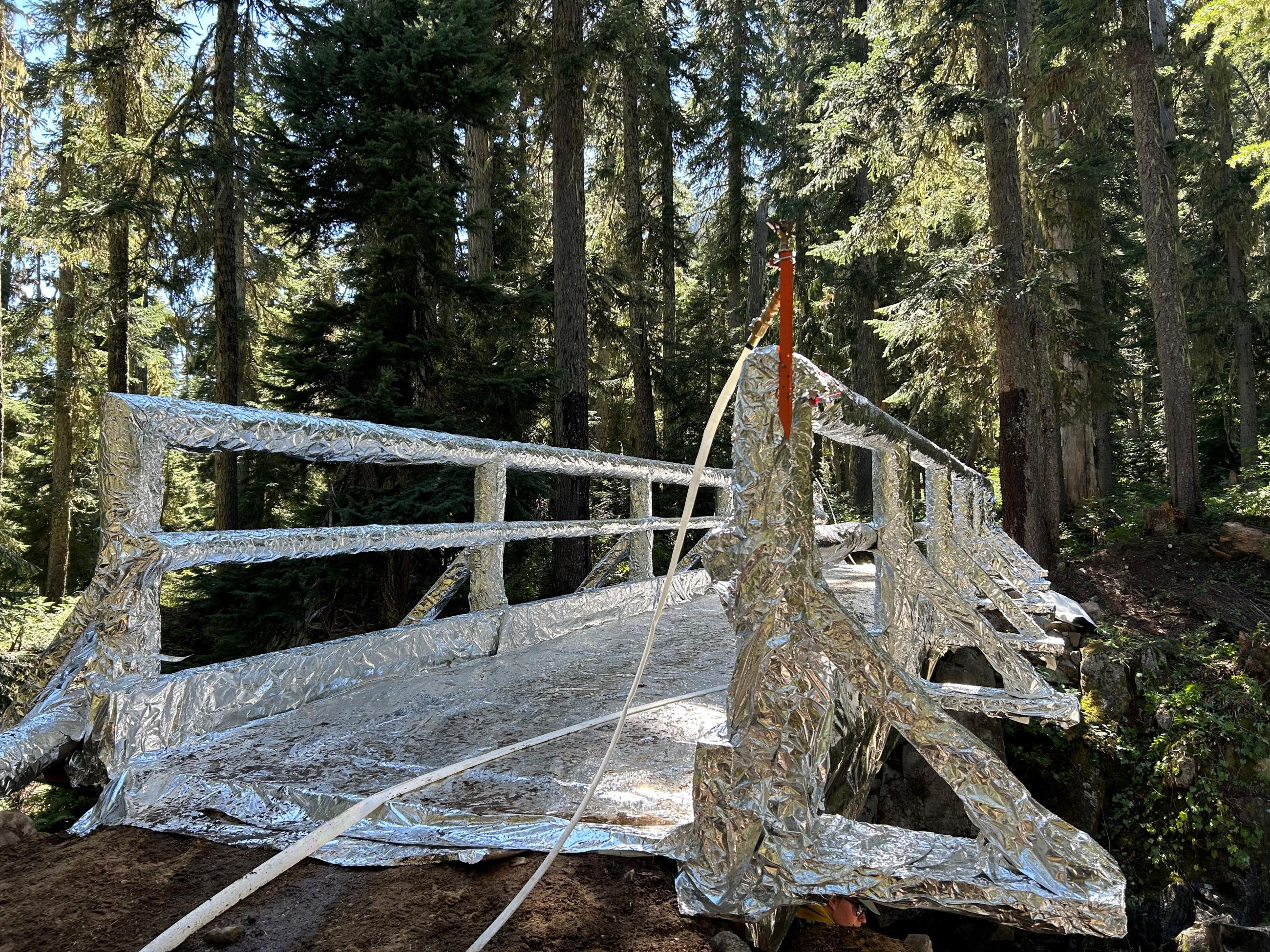 A stock bridge wrapped in silver aluminized fire-resistant material in a forest area