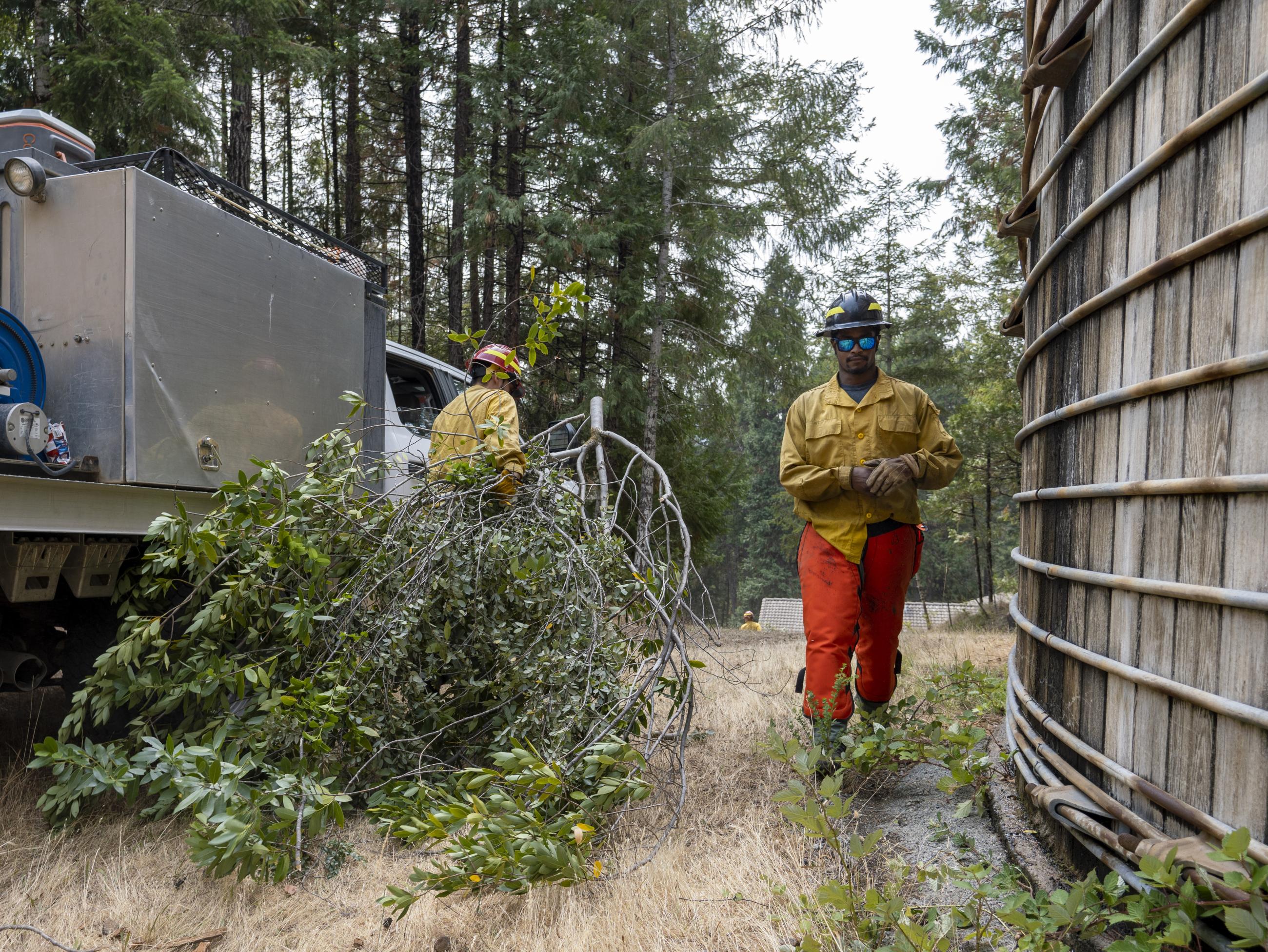 Firefighters remove debris as part of a structure prep operation in Gasquet in advance of Smith River Complex Fire.
