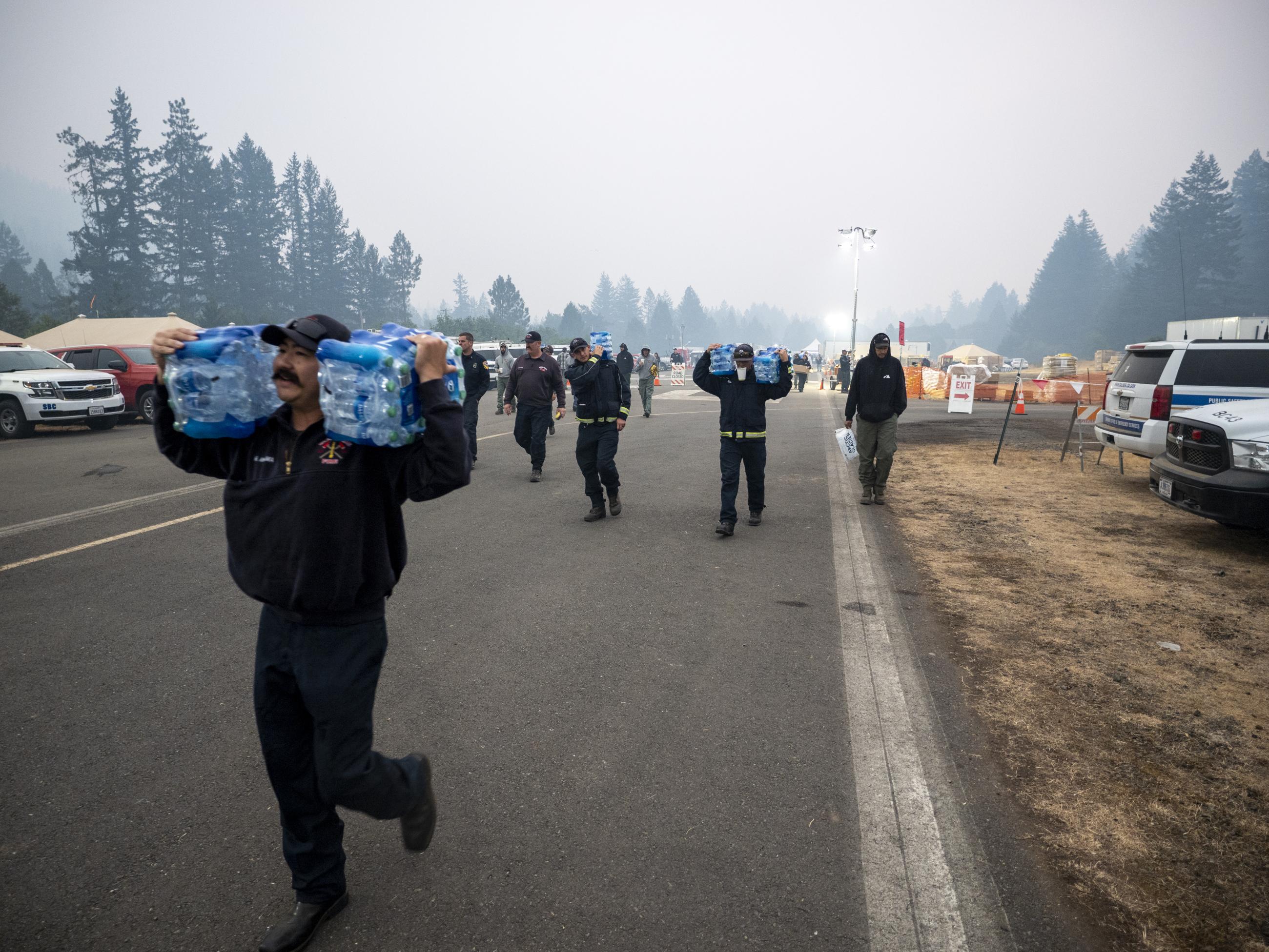 Firefighters carry water at Gasquet Fire Camp. August 24, 2023