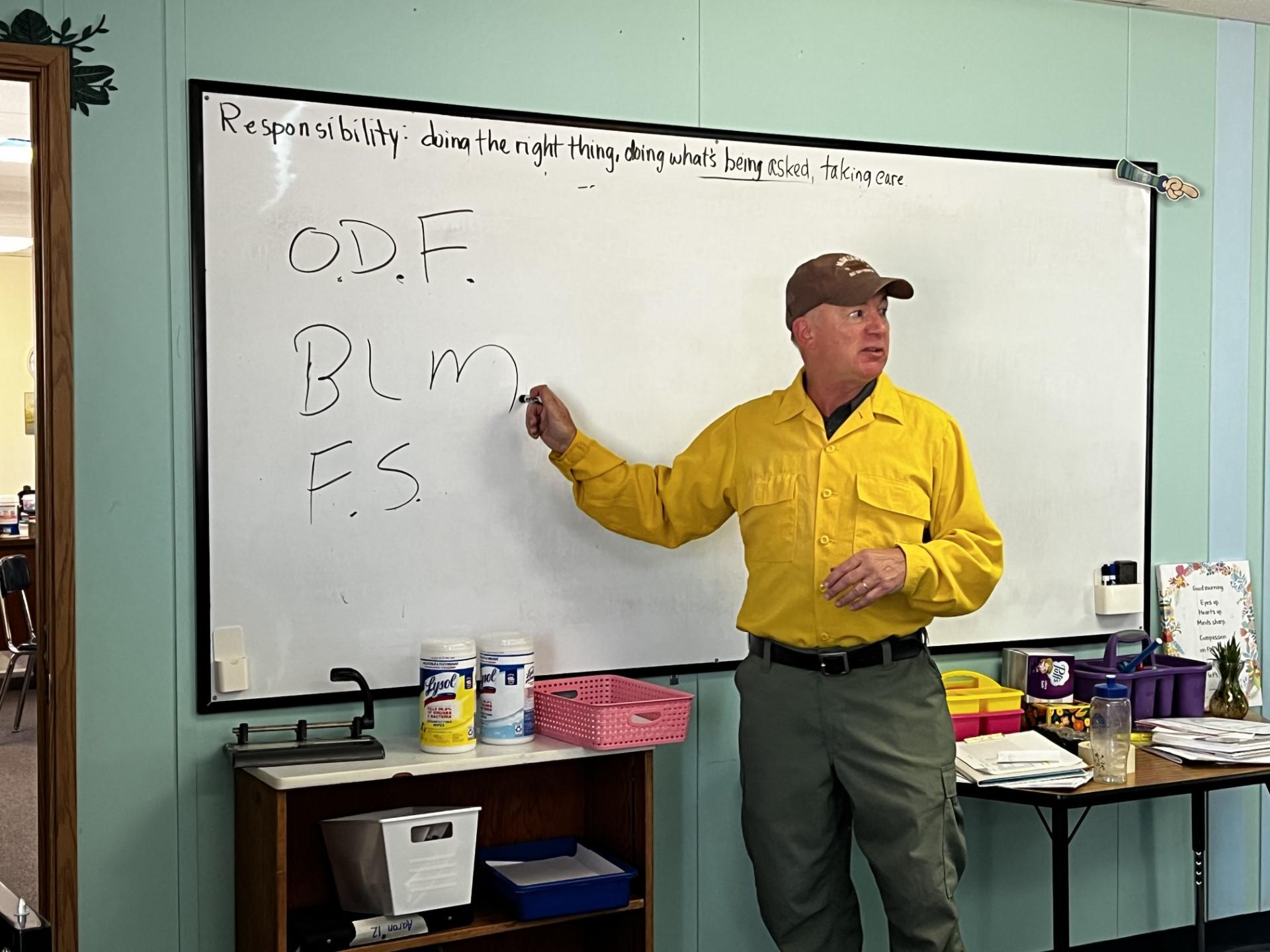 Firefighter stands by white board that lists different agencies: ODF, BLM, FS