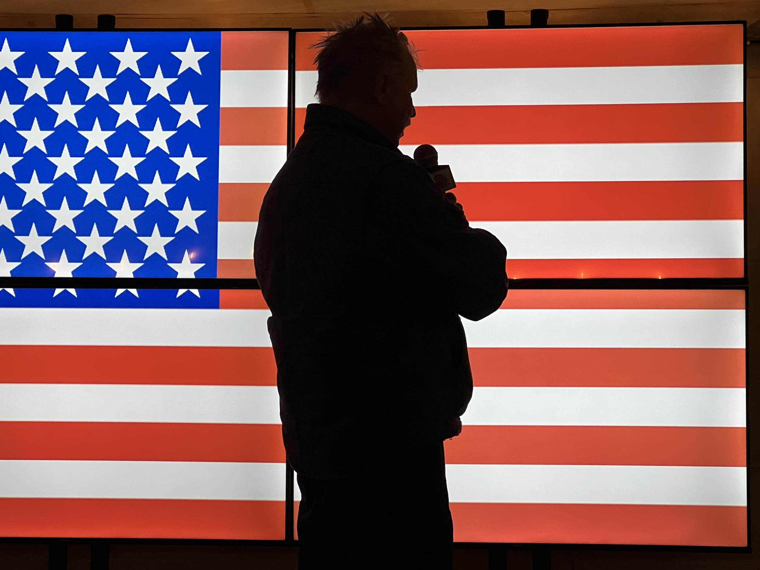 Image shows a silhouette of Incident Commander Mike Wakoski in front of an American Flag.  