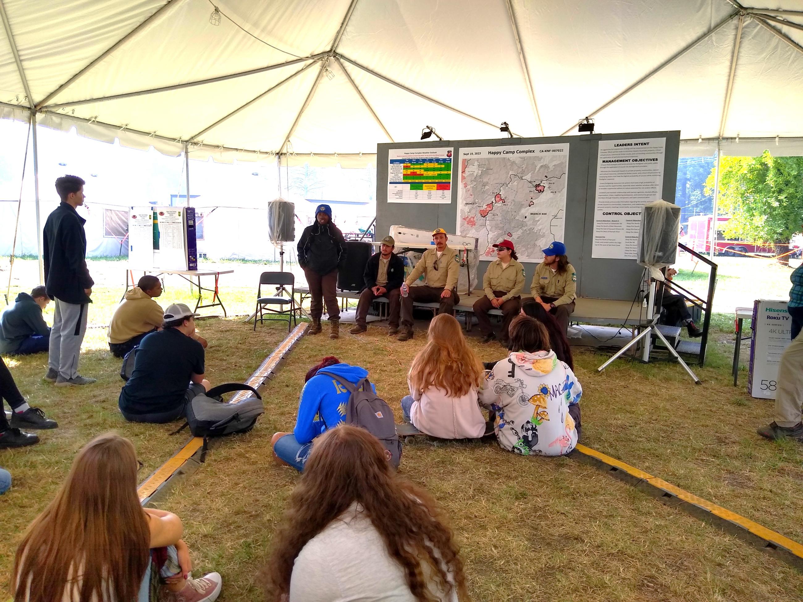 This photo shows members of the California Conservation Corps discussing employment opportunities with Happy Camp High School students on a fire camp tour.