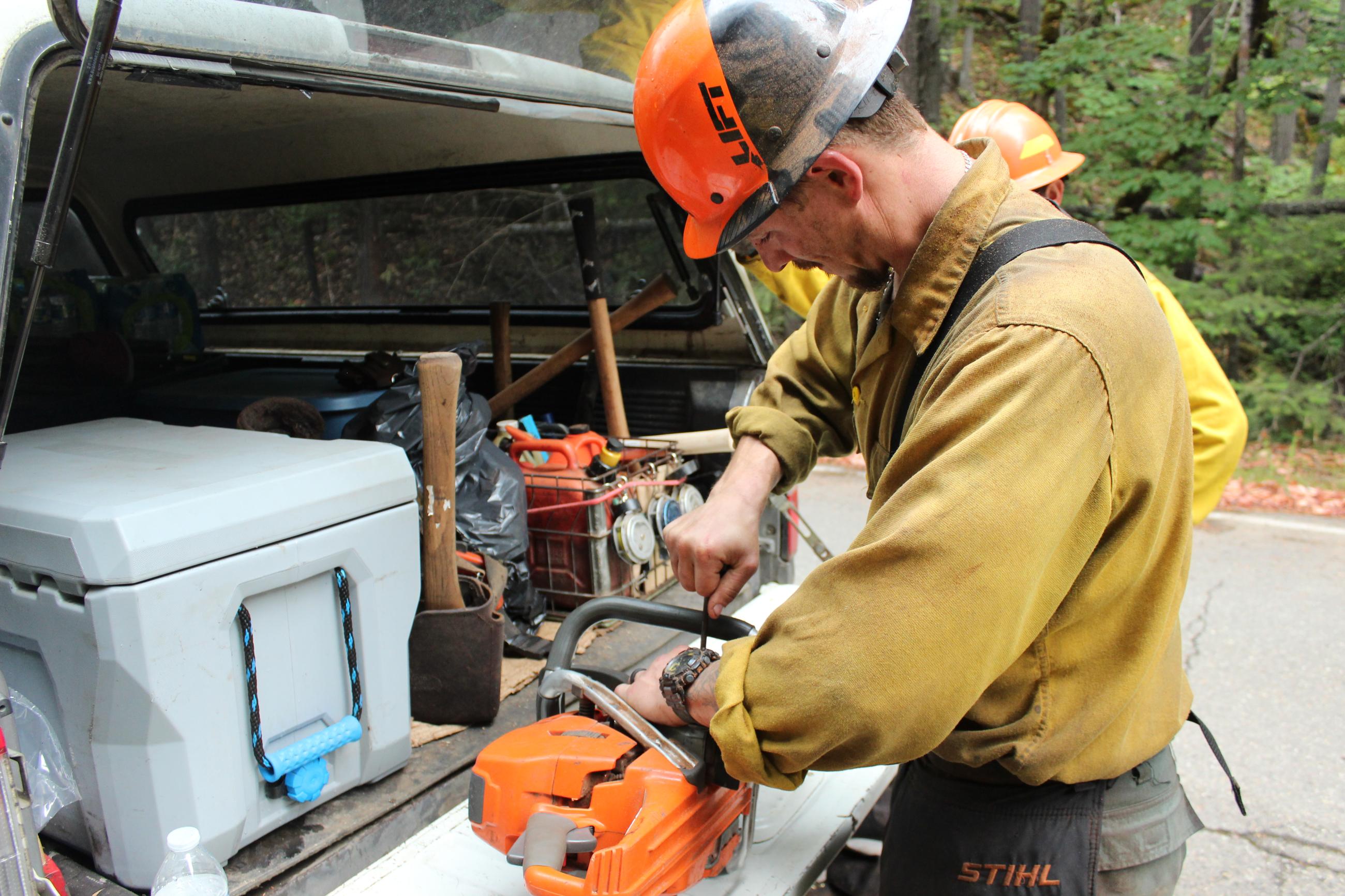 A feller on the Chilcoot Fire prepares his saw for operation