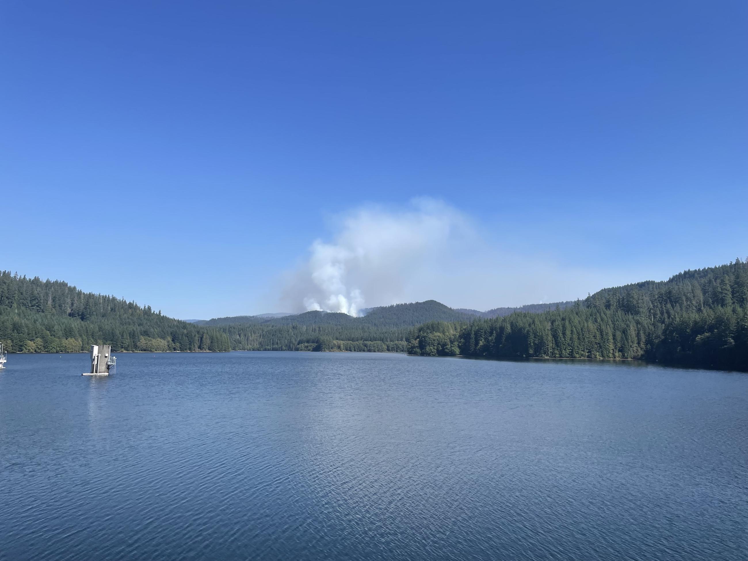 smoke rises off the ridge behind the reservior