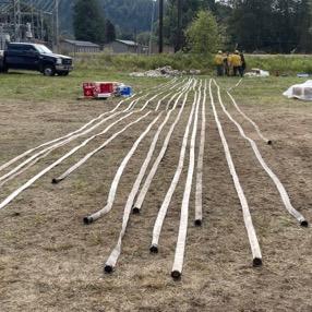 Several sections of hose are laid out on the ground for inspection