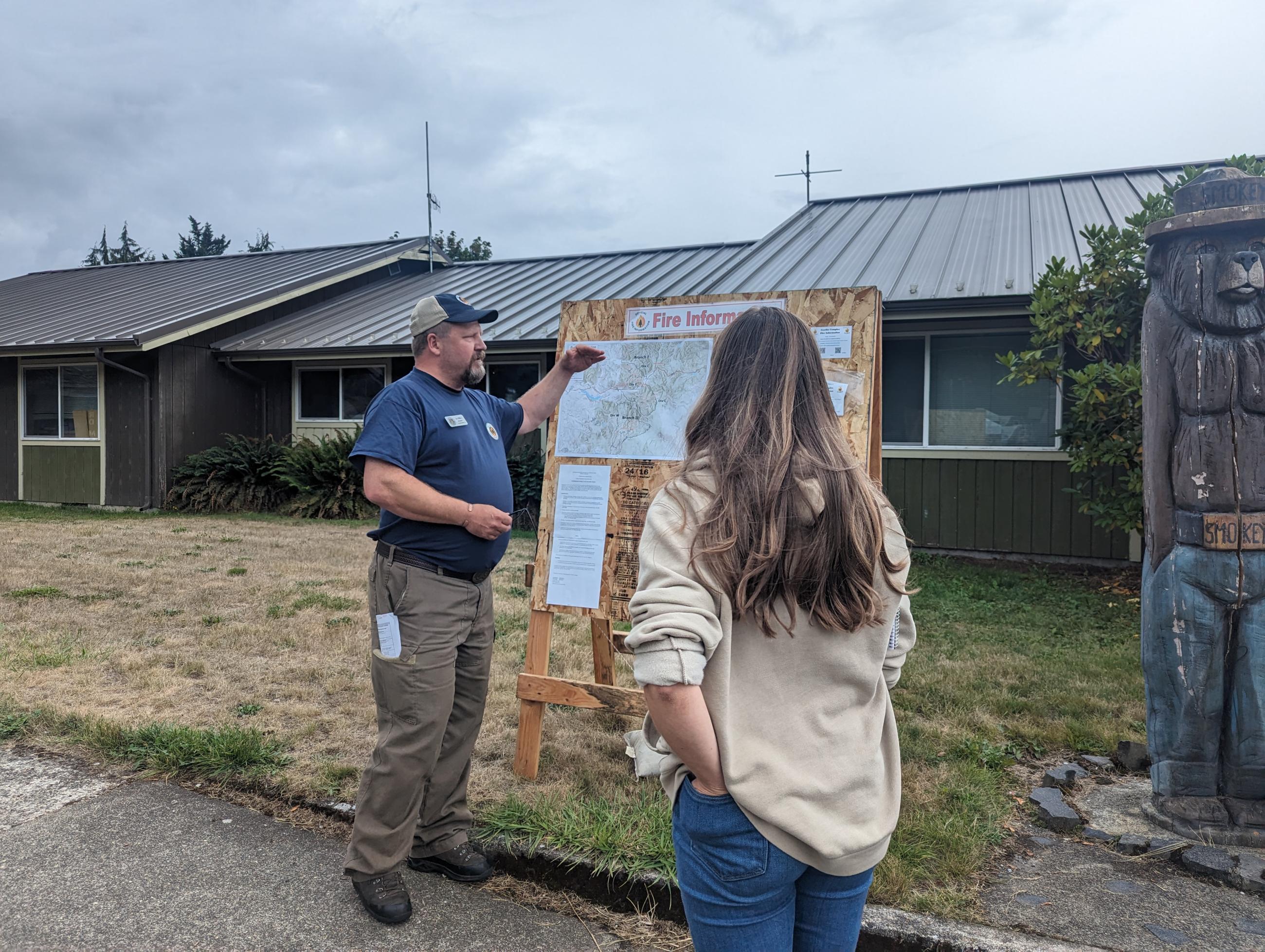 A PIO provides fire information to a member of the public at one of the trapline fire information boards