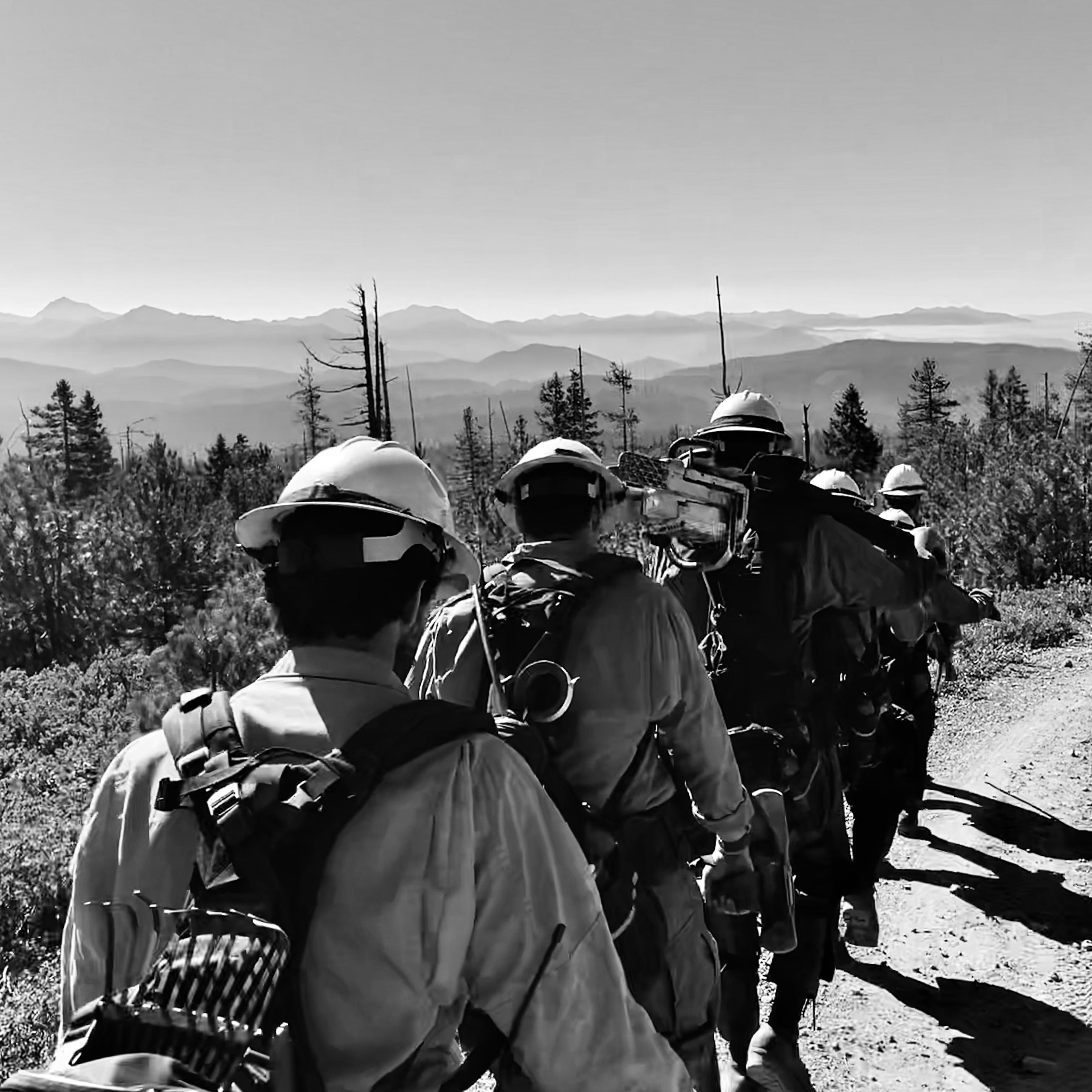 A black and white photo of a firefighting crew hiking to work.