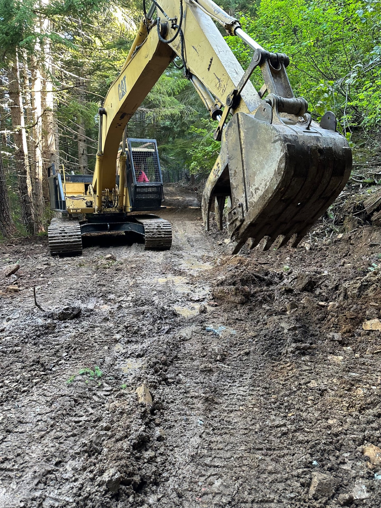 Excavator moves material along a dirt road