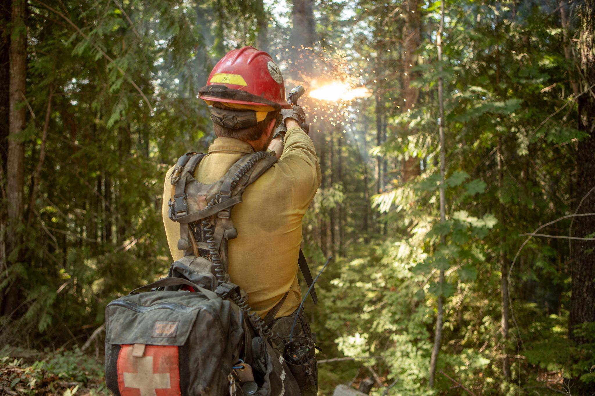 This is an image of a firefighter shooting a very pistol during backburn operations