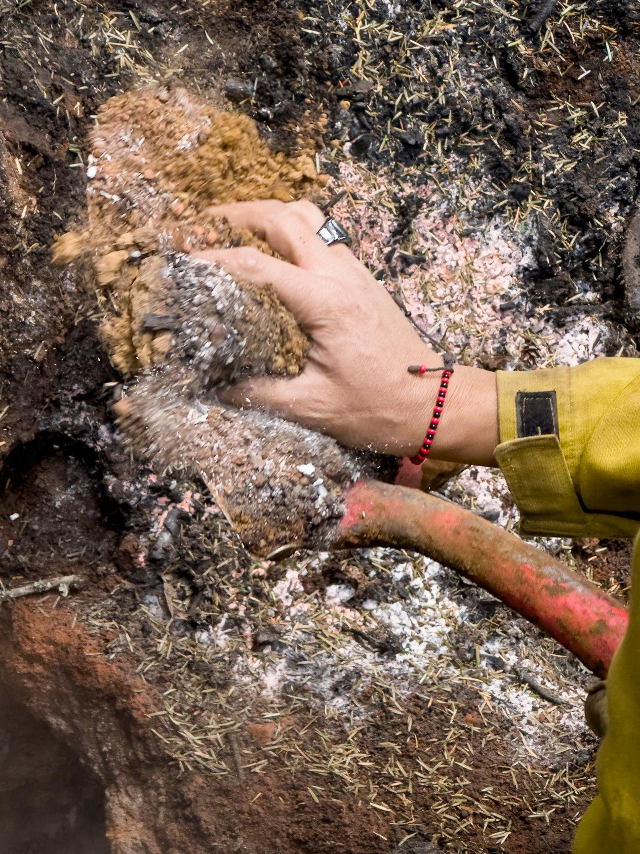 A hand appears in the soil and ash to find whether heat exists