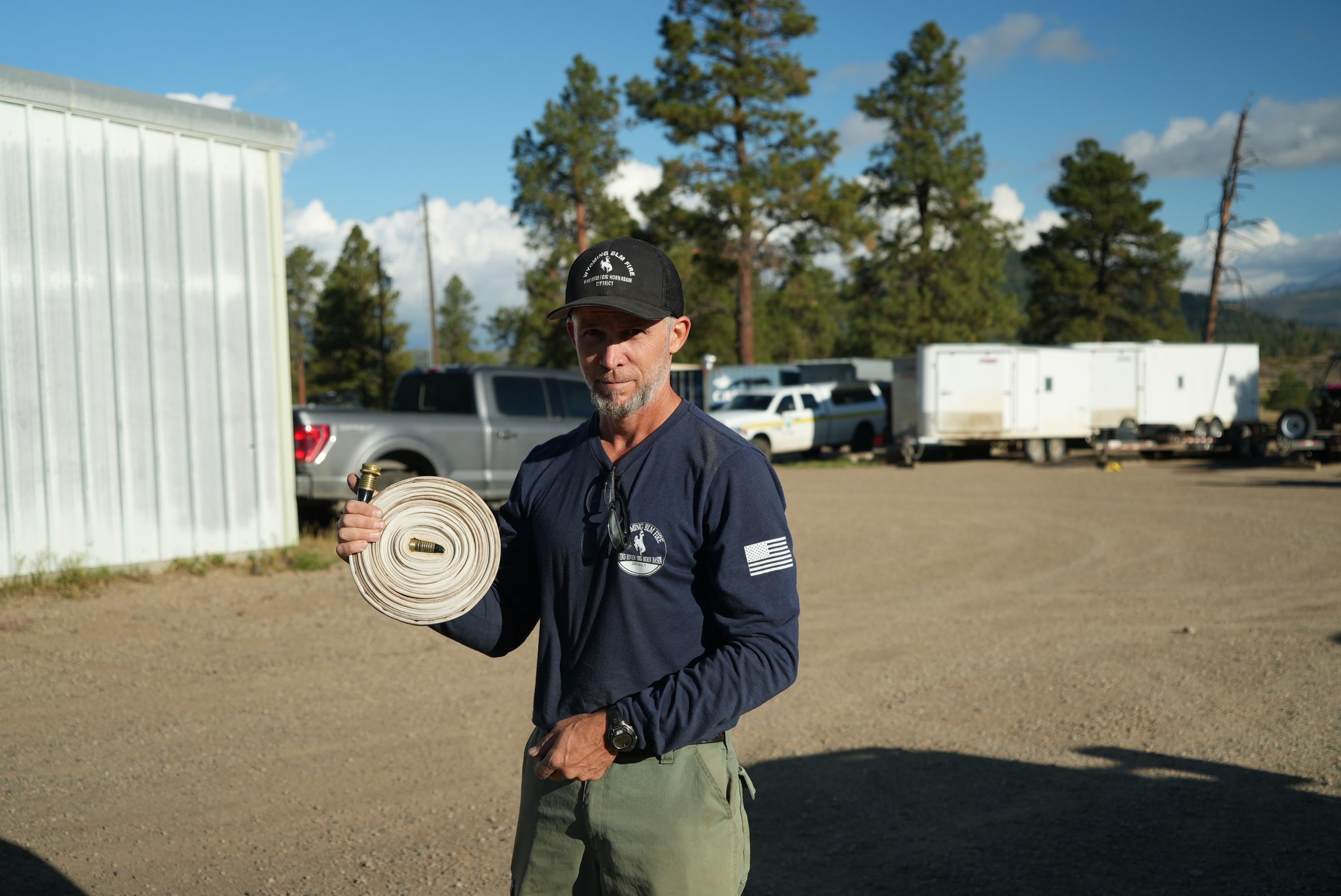 Firefighter Bryan Kilcrease holds fire hose he just rolled up now that is no longer needed.