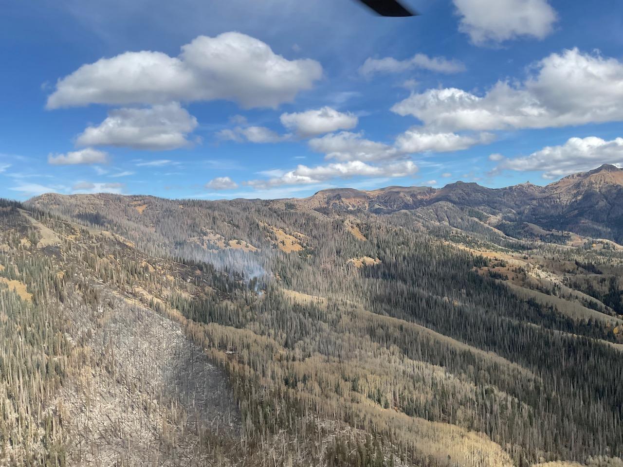 This is an aerial view showing several whisps of smoke rising from a rocky mountain ridge.