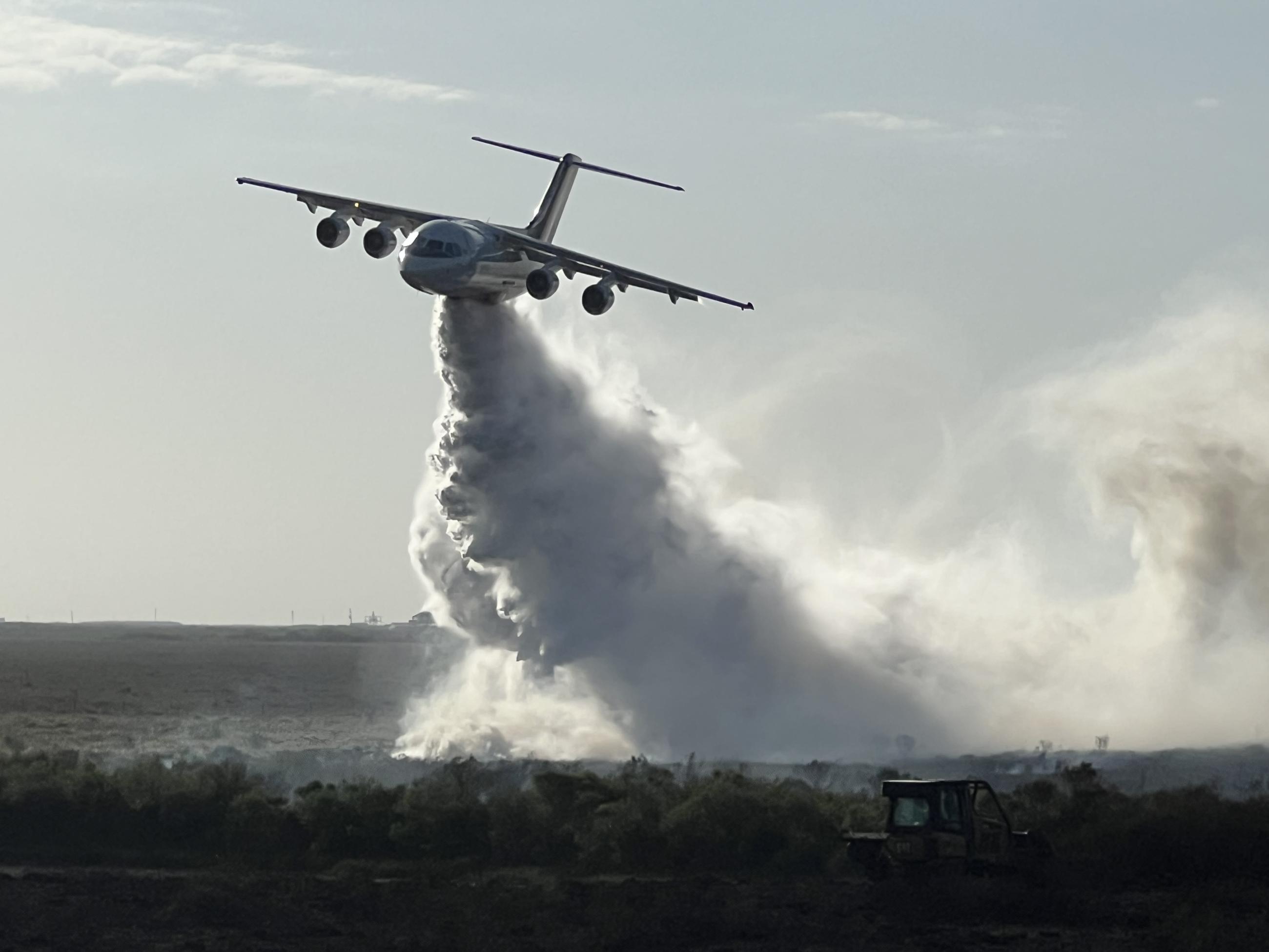 large airtanker drops water on marshy vegetation