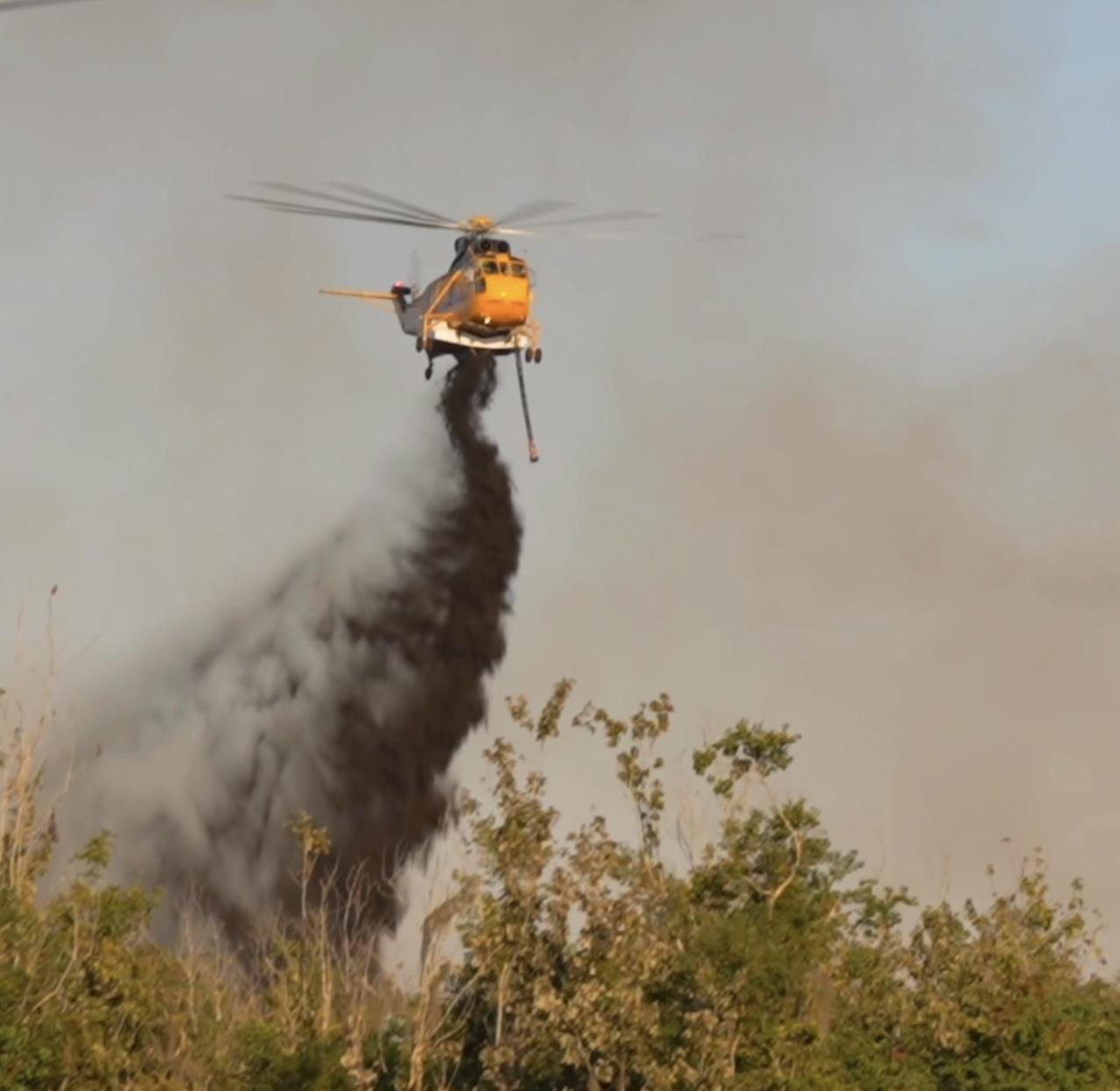 A helicopter drops water on the fire