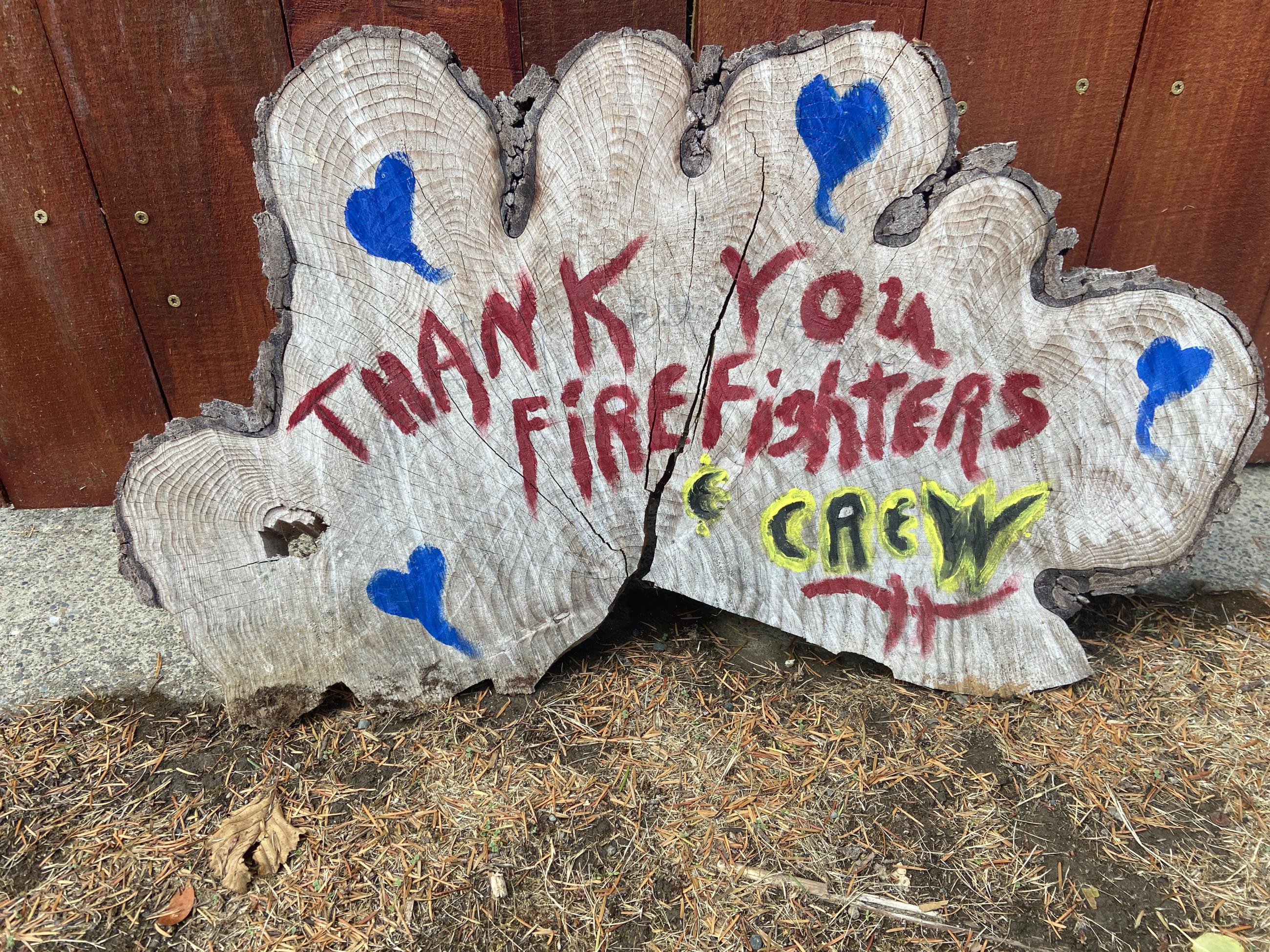 Piece of wood painted to say thank your firefighters in red with blue hearts